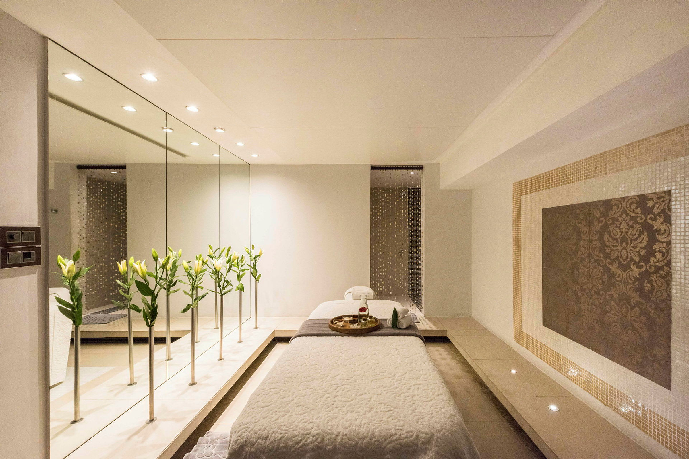 En elegant spa-omgivelse med en massasjebenk, blomster og et speil. (AI-generert tekst)
