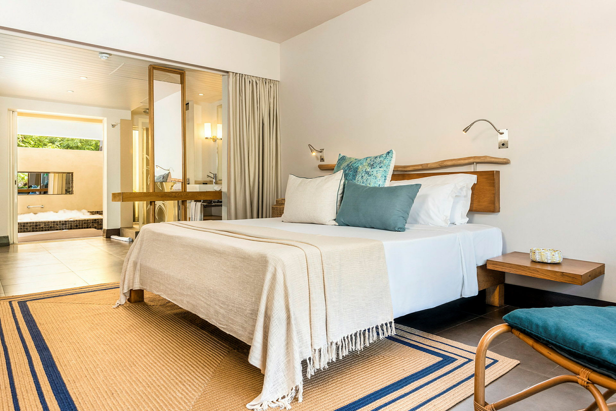 Et moderne hotellrom med en stor seng, puter og inngang til bad med boblebad. (AI-generert tekst)
