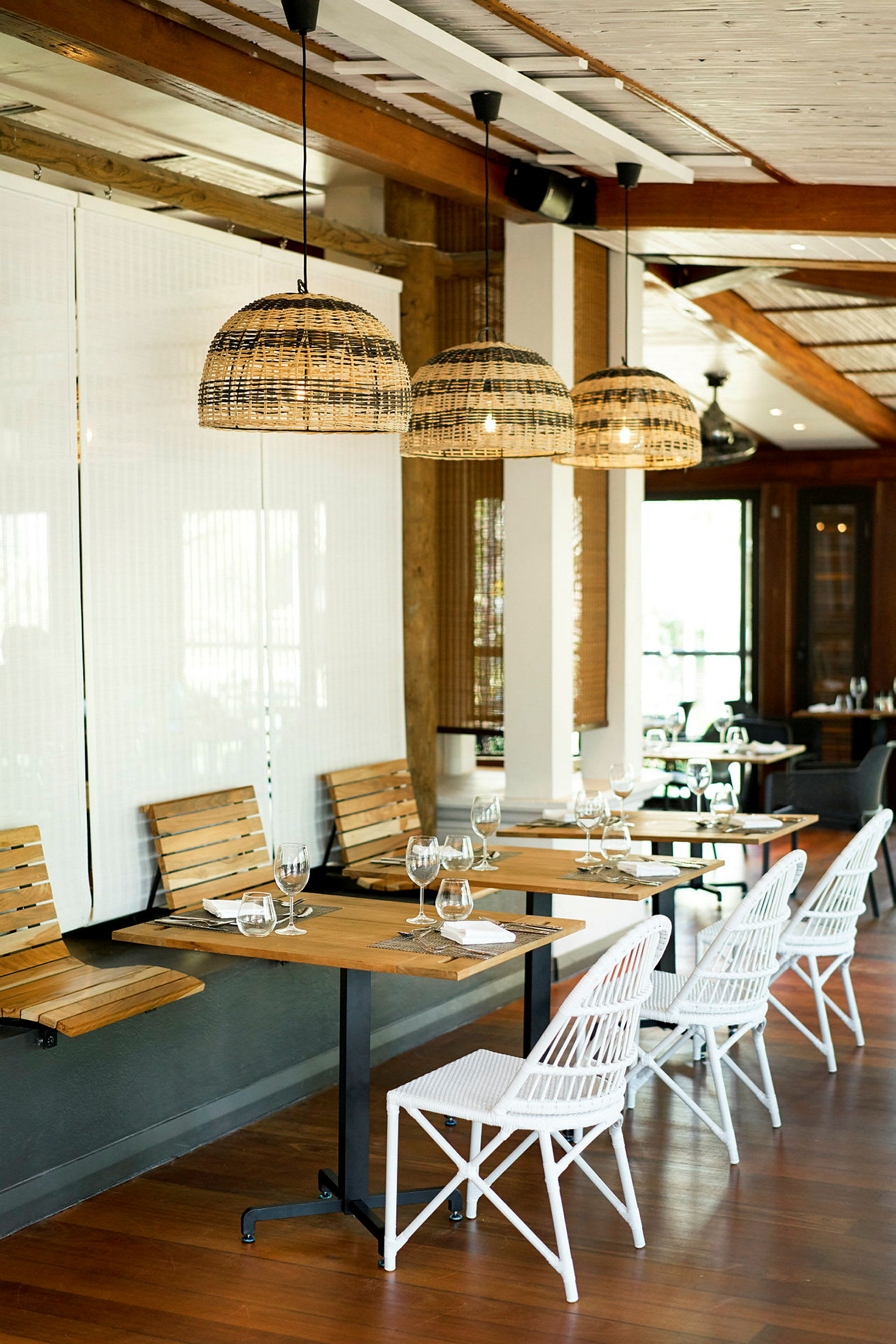 En restaurant med trebord, hvite stoler og hengende lamper av rotting. (AI-generert tekst)