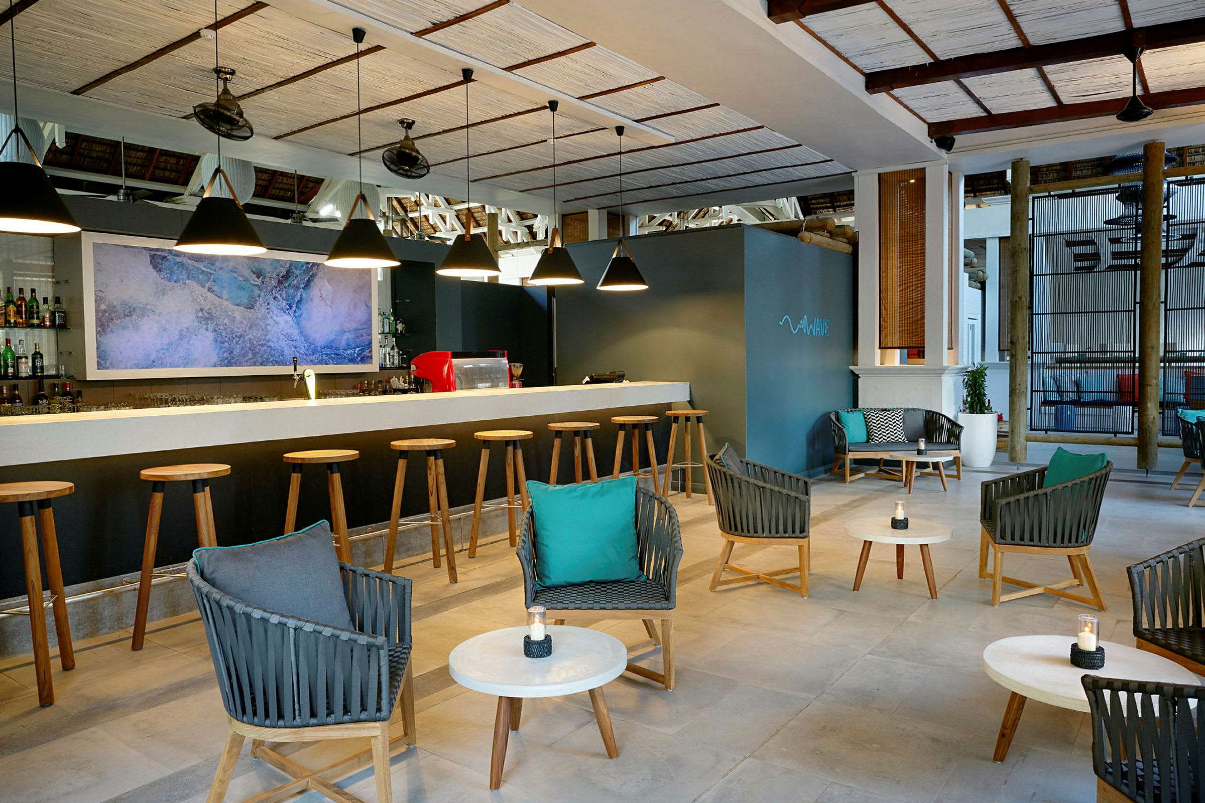 En moderne bar med en rekke barkrakker foran en bardisk, koselig sittegruppe med stoler og bord i forgrunnen. (AI-generert tekst)