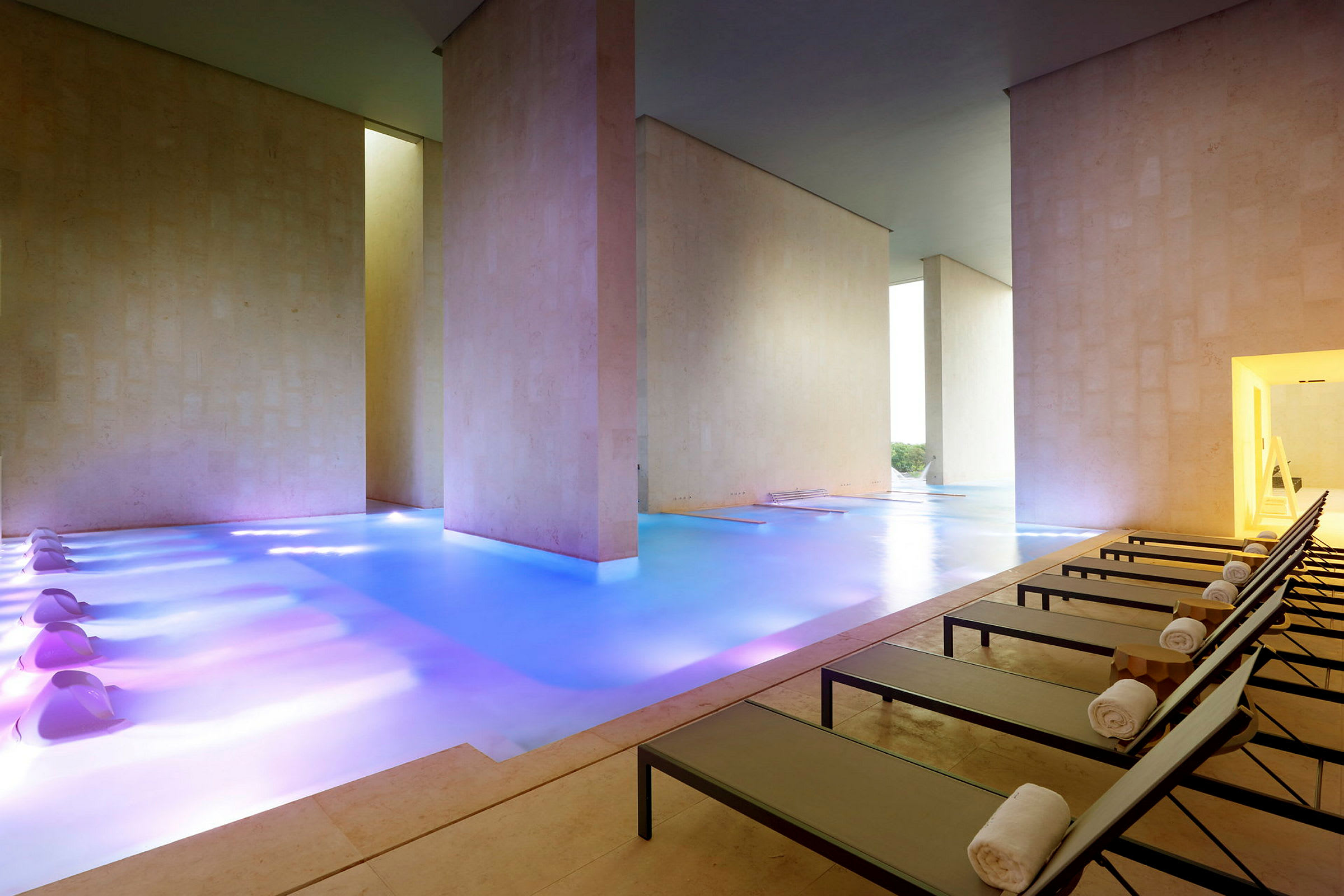 Et elegant innendørs spa med et oppvarmet basseng i et moderne miljø og solsenger langs den ene siden. (AI-generert tekst)