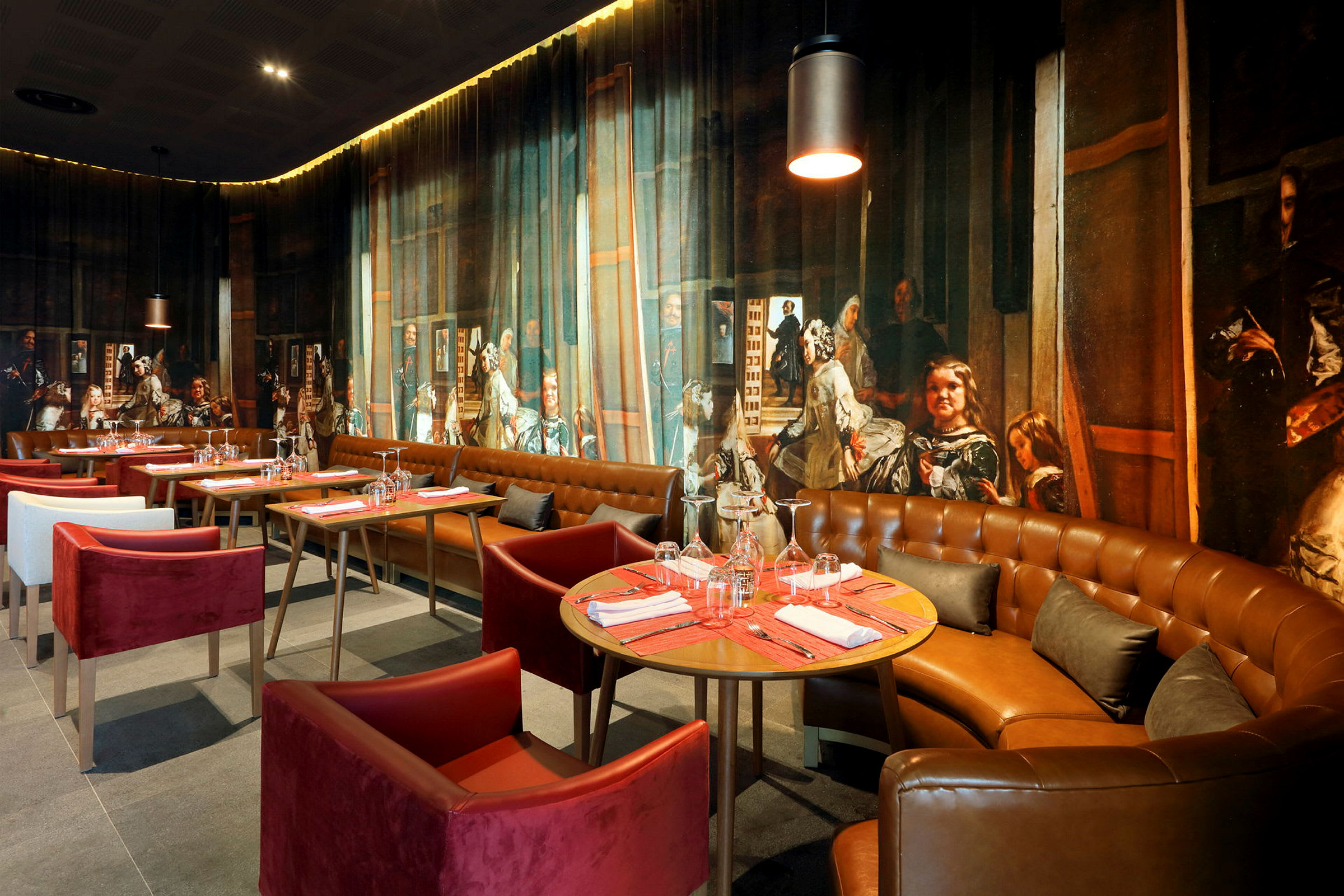 En restaurantinteriør med spisebord og stoler, elegant dekor samt en veggdekorasjon som viser et detaljert maleri. (AI-generert tekst)