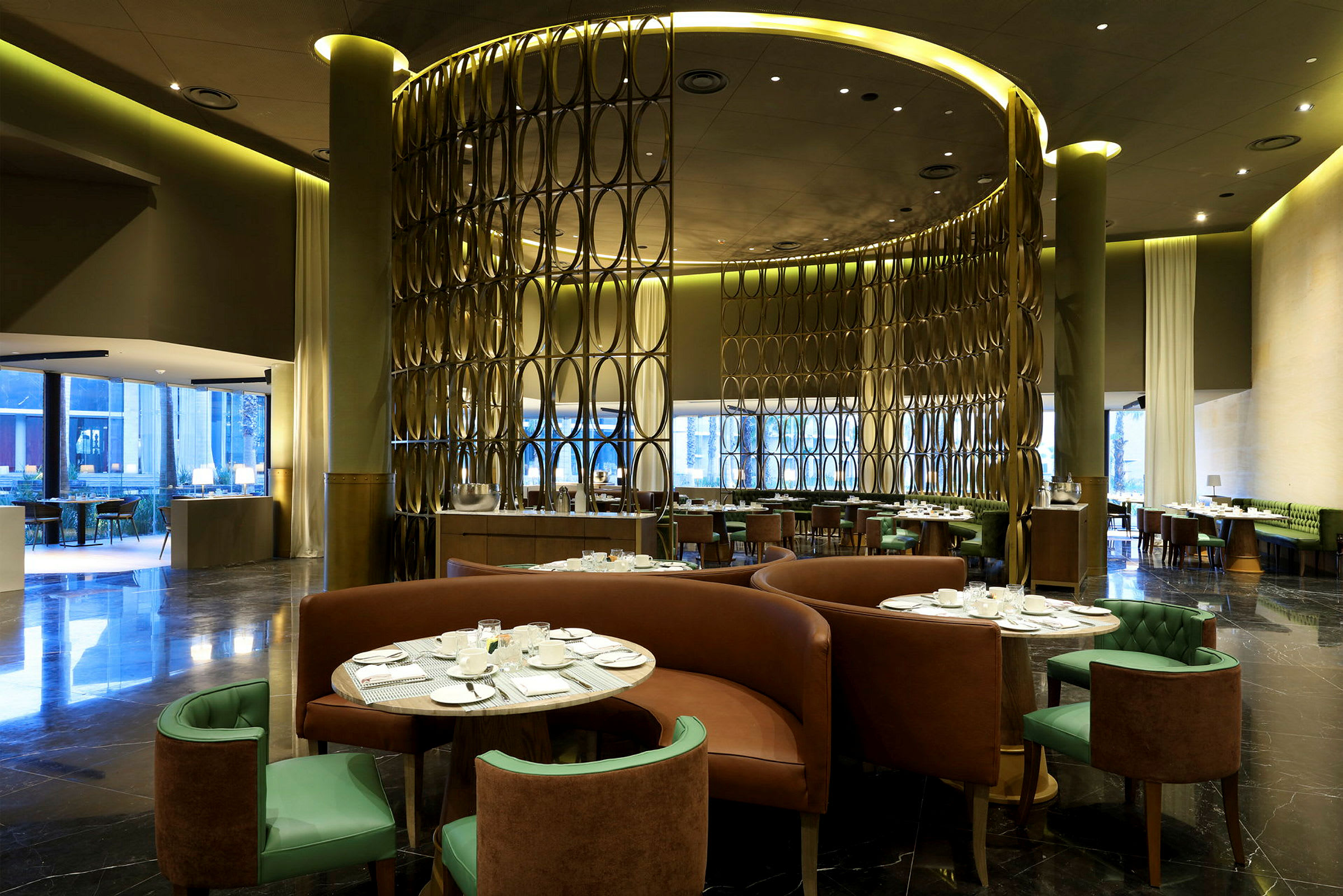 Interiør av en restaurant med moderne møbler og dekor. Runde bord med duk og stoler omgitt av dekorative skillevegger. (AI-generert tekst)