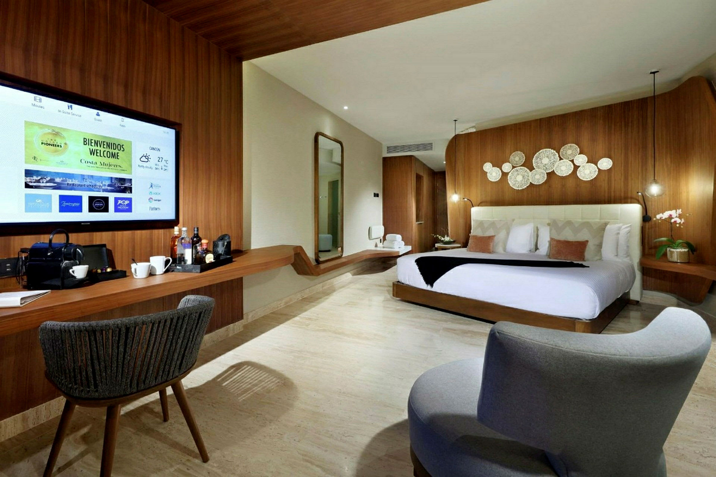 Et moderne hotellrom med en komfortabel seng, dekorative detaljer på veggen, en stor TV og en sitteplass. (AI-generert tekst)