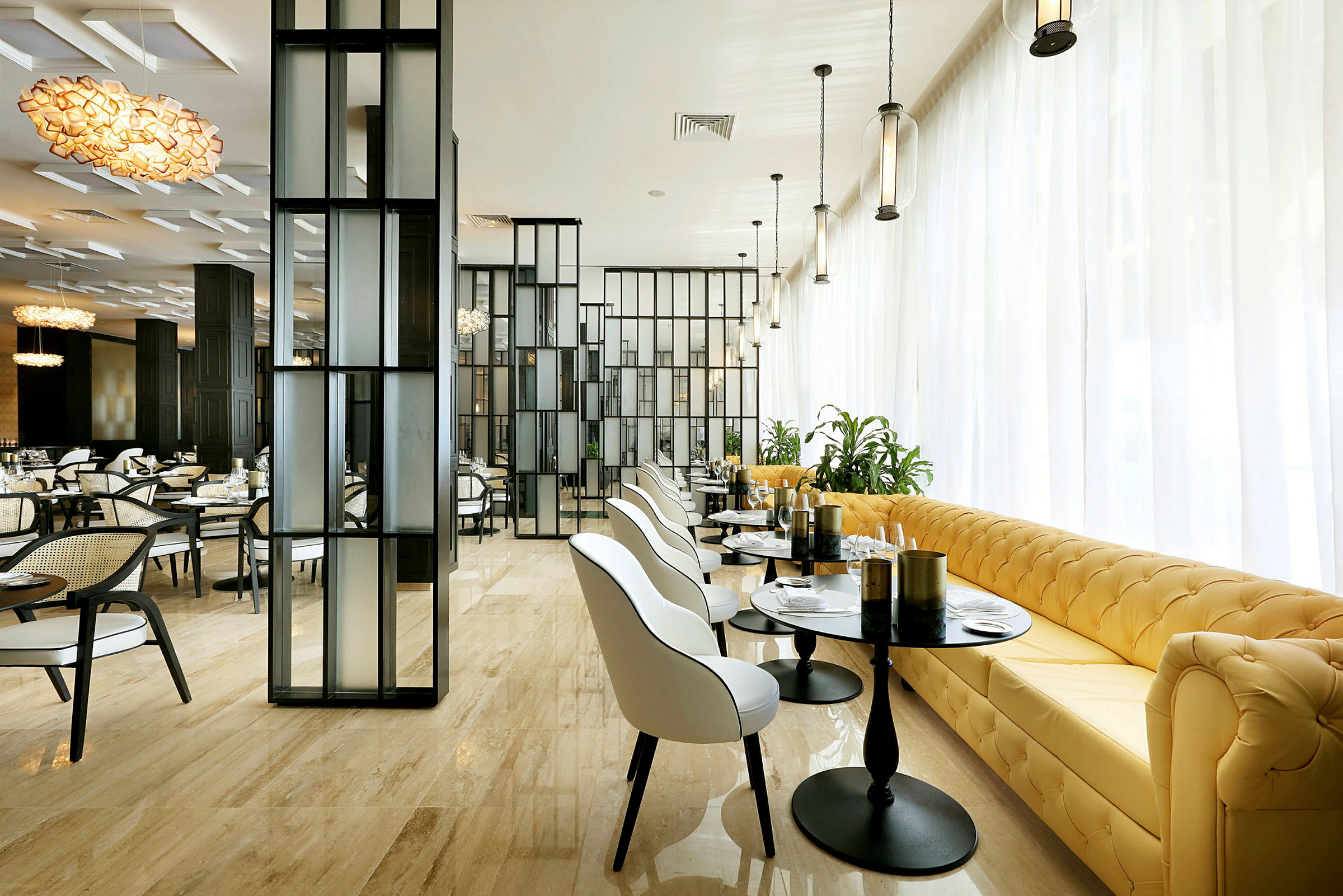 Et moderne spiseområde med elegant interiør, hvite stoler, gule sofaer, glassbord og store vindusflater. (AI-generert tekst)
