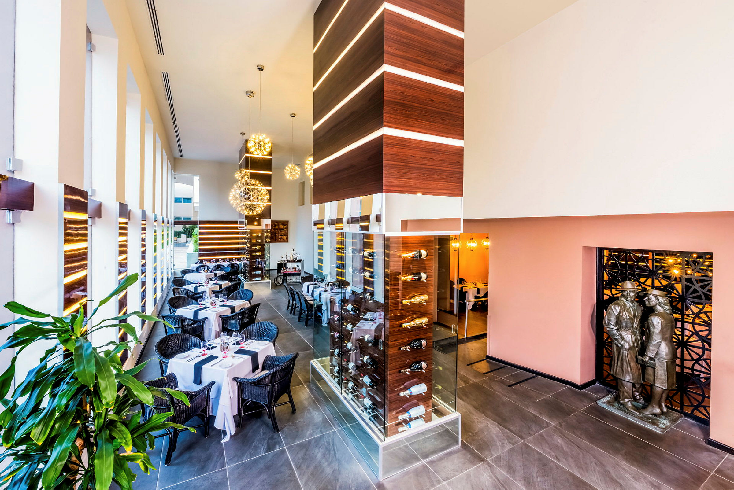 Interiør av en moderne restaurant med dekkede bord, elegante dekorasjoner og et glassskap med flasker. (AI-generert tekst)