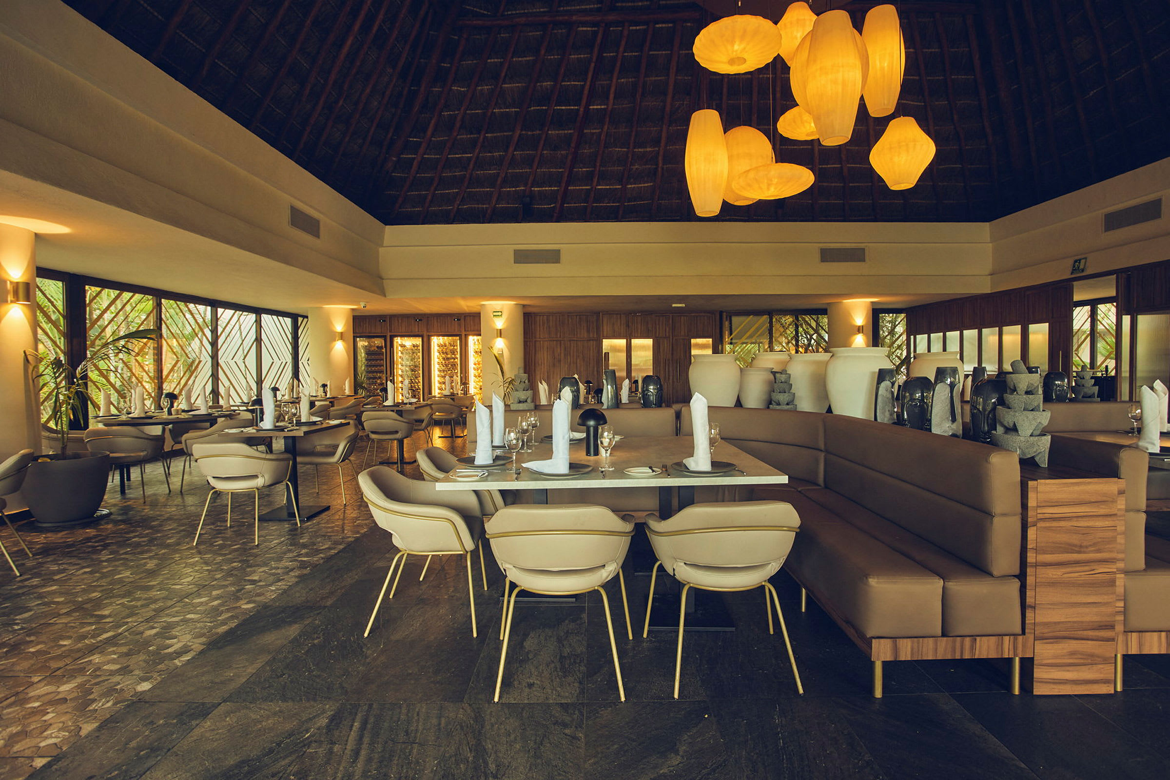 Bilde av en elegant restaurant med dekkede bord, moderne stoler og store dekorative vaser. Taket er høyt med synlige trekonstruksjoner og rommet har varm belysning. (AI-generert tekst)