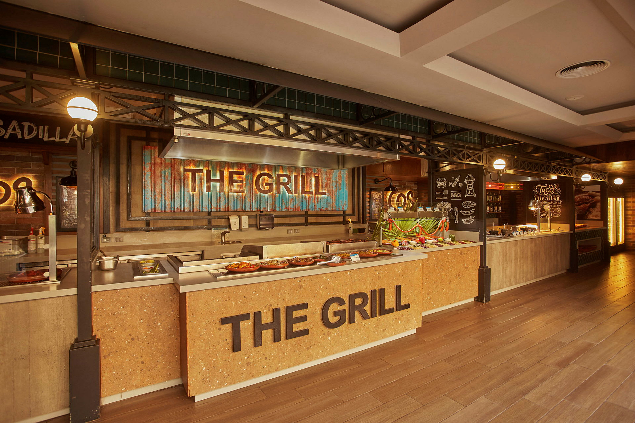 Bufféområde med en grillstasjon merket 'The Grill' og matoppsett. (AI-generert tekst)