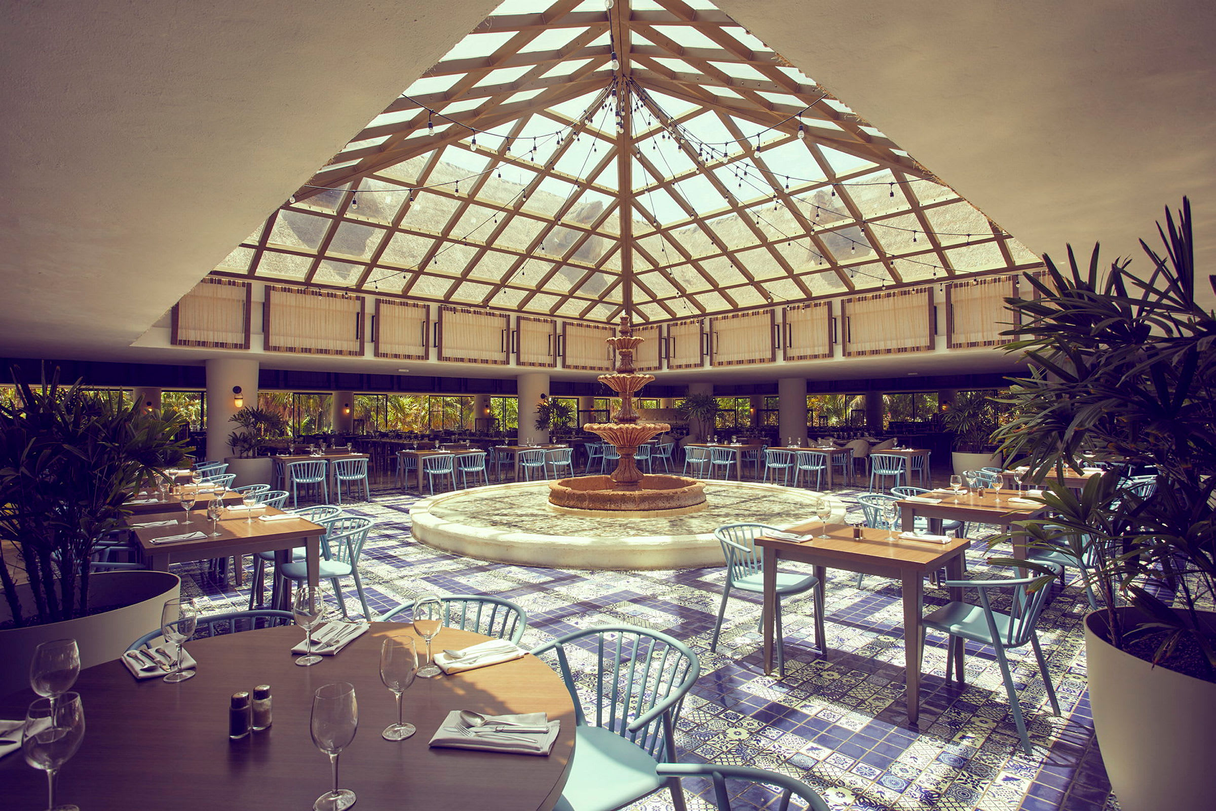 Bilde av en restaurant med et glasstak, en fontene i midten og sitteplasser rundt. (AI-generert tekst)