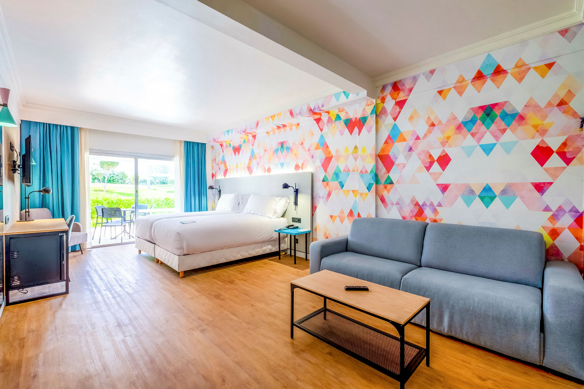 Hotellrom med stor seng, sittegruppe og fargerikt veggdesign. (AI-generert tekst)