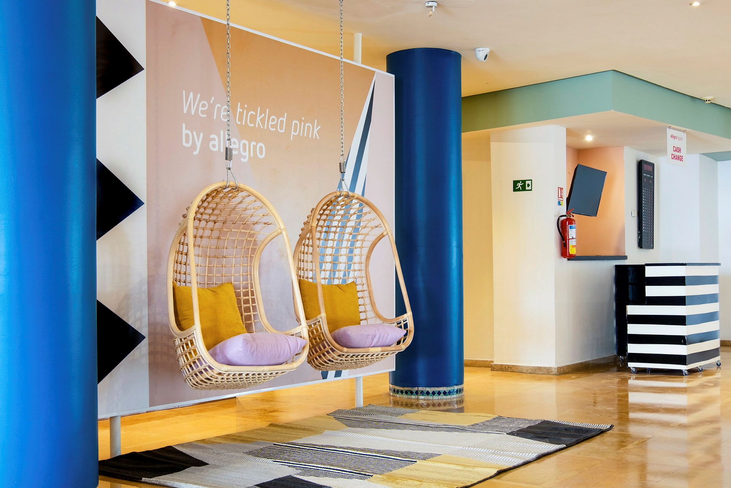 To hengende stoler med puter i en hotellobby. (AI-generert tekst)