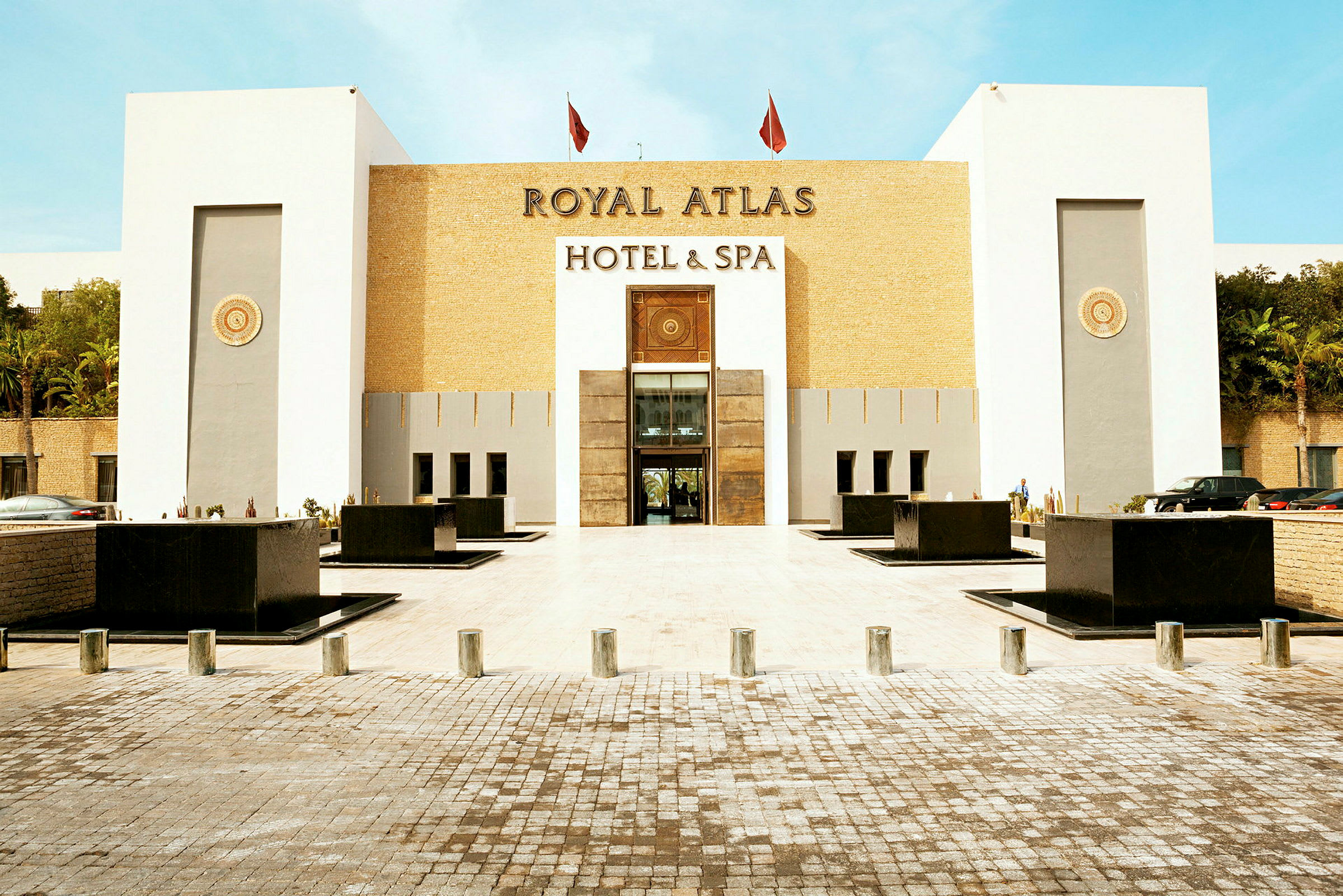 Forsiden av et hotell kalt Royal Atlas Hotel & Spa, med en moderne og stilren fasade. (AI-generert tekst)