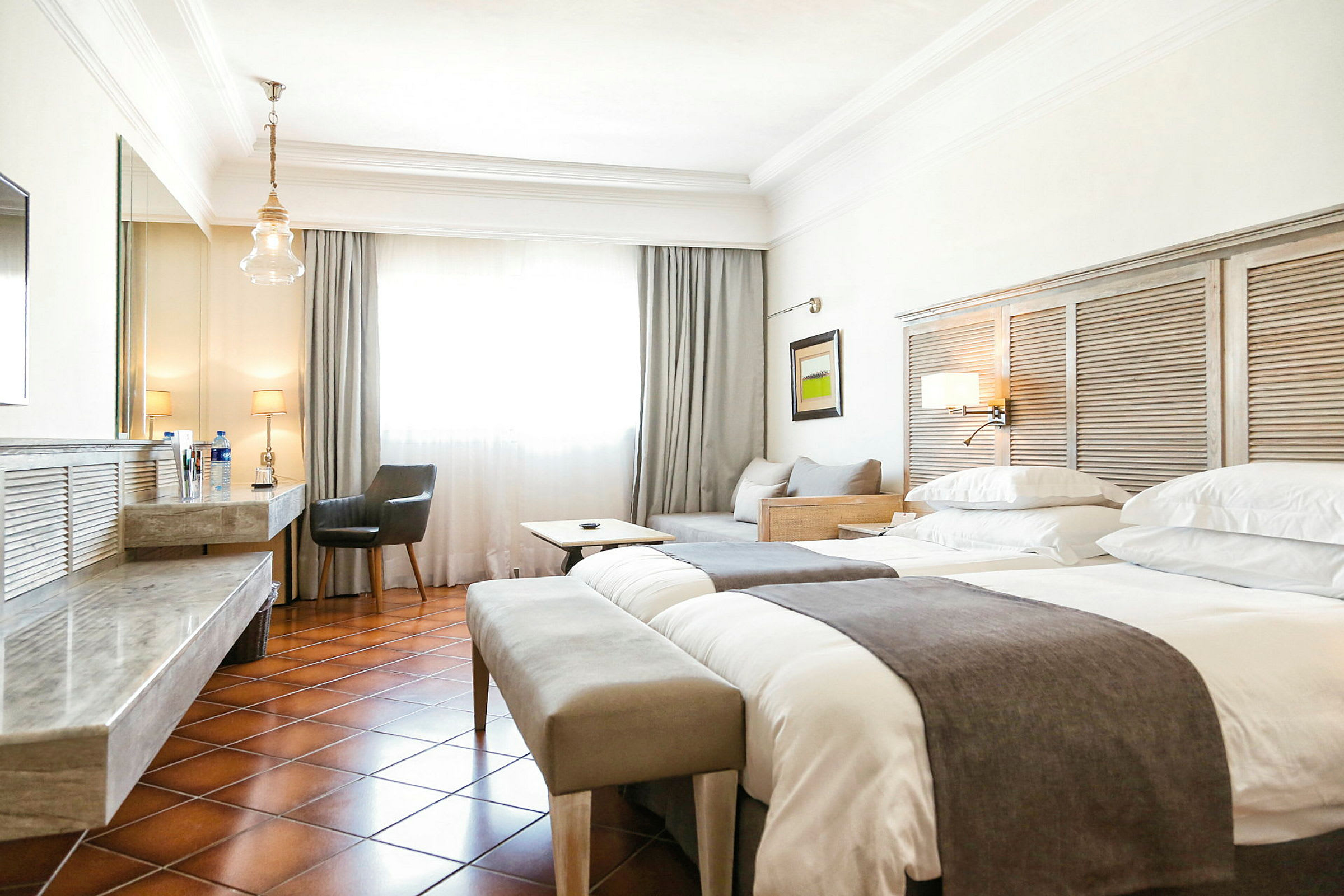Hotellrom med to senger, sitteplasser og skrivebord. (AI-generert tekst)