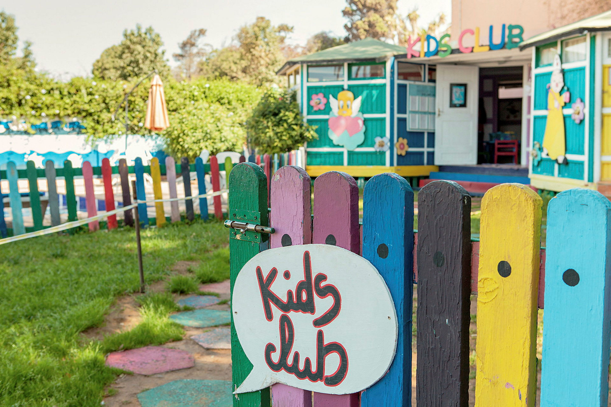 En lekeplass med et fargerikt gjerde og et skilt som sier "Kids Club". (AI-generert tekst)
