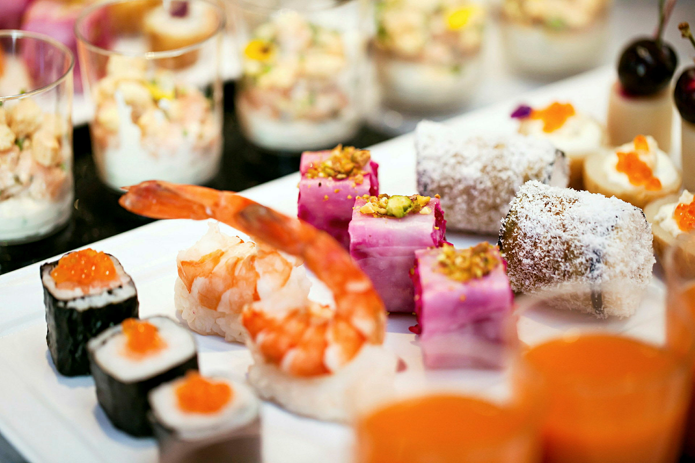 Ulike typer delikate småretter på et fat, inkludert sushi, reker og desserter. (AI-generert tekst)