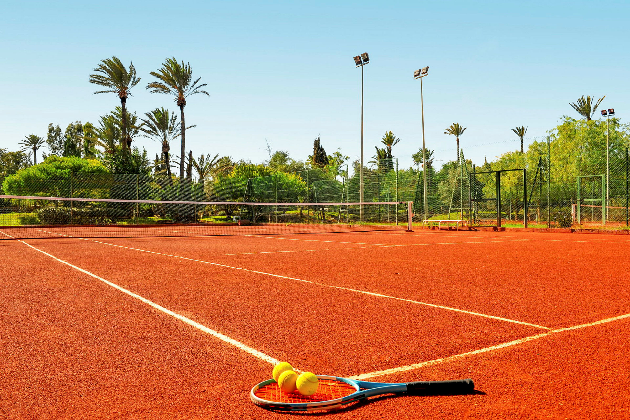 Tennisbane med racket og baller på bakken. (AI-generert tekst)