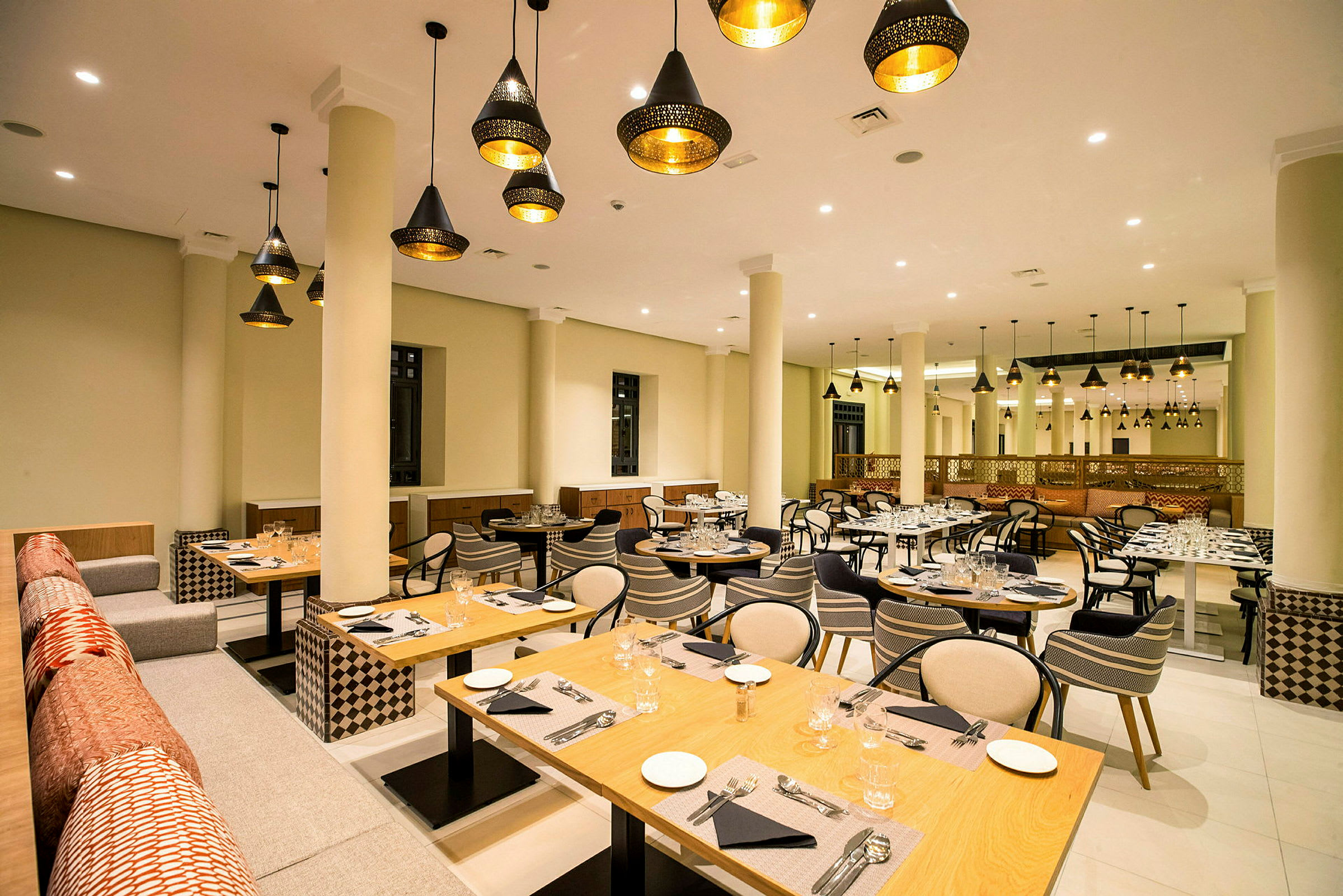 Restaurant med dekorative lamper, dekkede bord og sitteplasser. (AI-generert tekst)