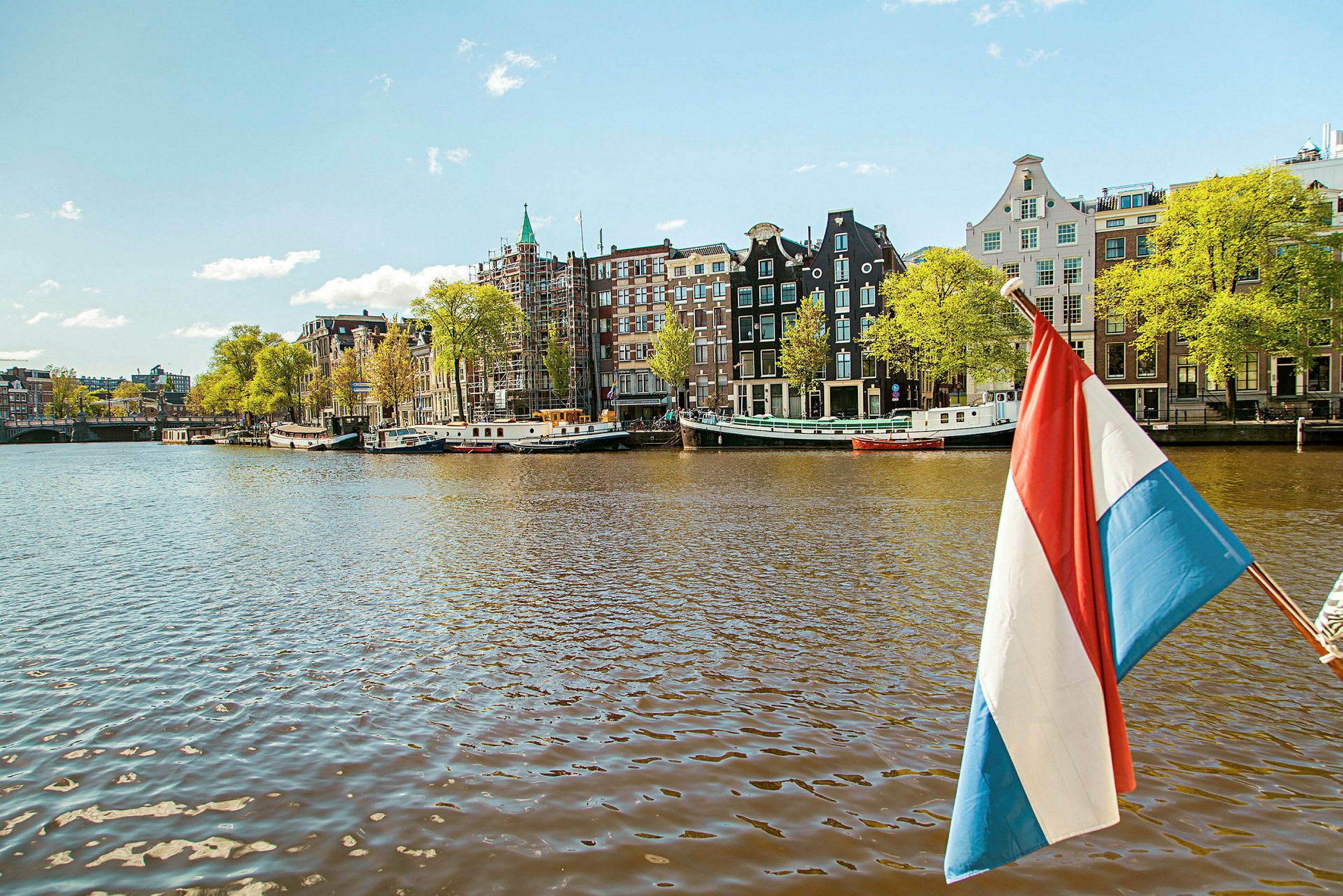 Et bilde av en kanal med hus på rekke, et nederlandsk flagg synlig i forgrunnen. (AI-generert tekst)