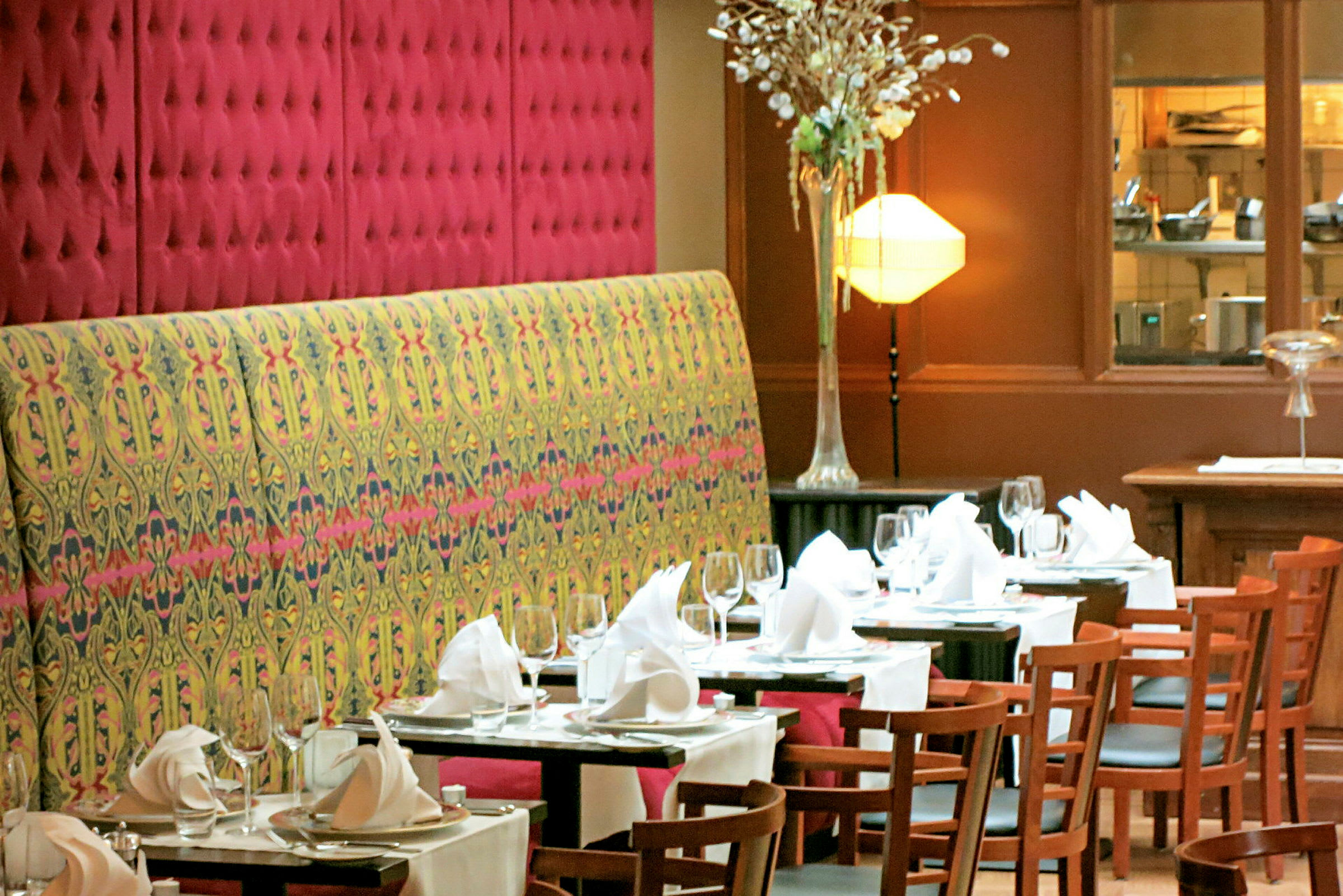 En restaurantinteriør med dekkede bord med hvite duker, glass, tallerkener og brettede servietter. (AI-generert tekst)