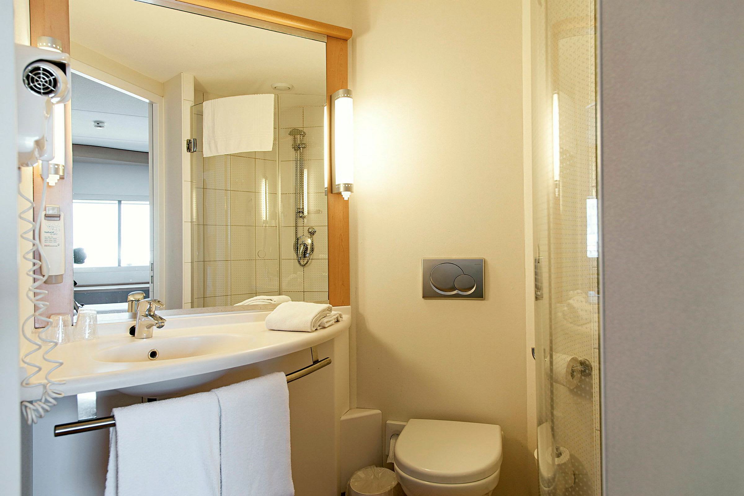 Et hotellbad med vask, toalett og dusj. (AI-generert tekst)