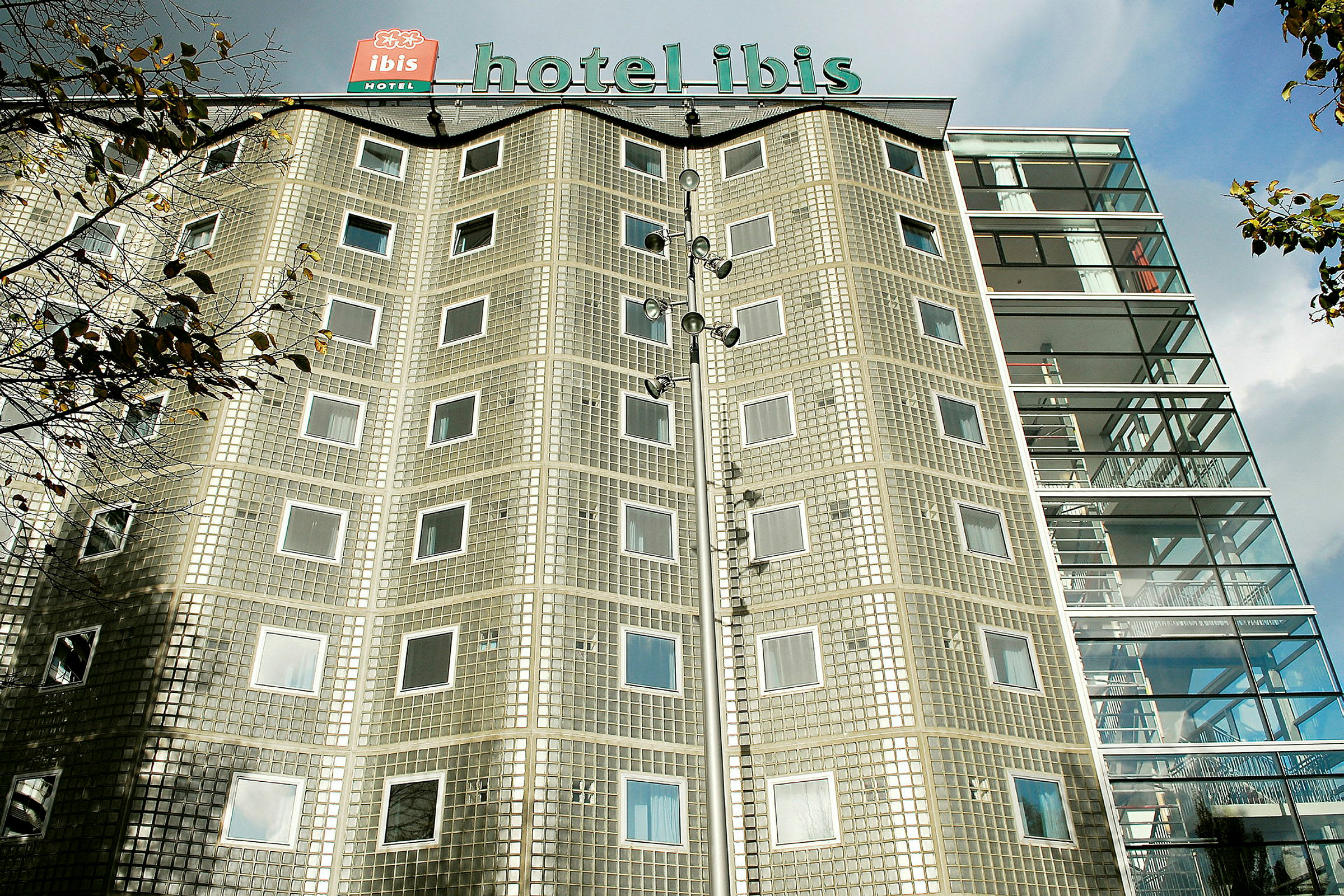 Bygning med hotellnavnet på taket og fasade av glassblokker samt vinduer. (AI-generert tekst)