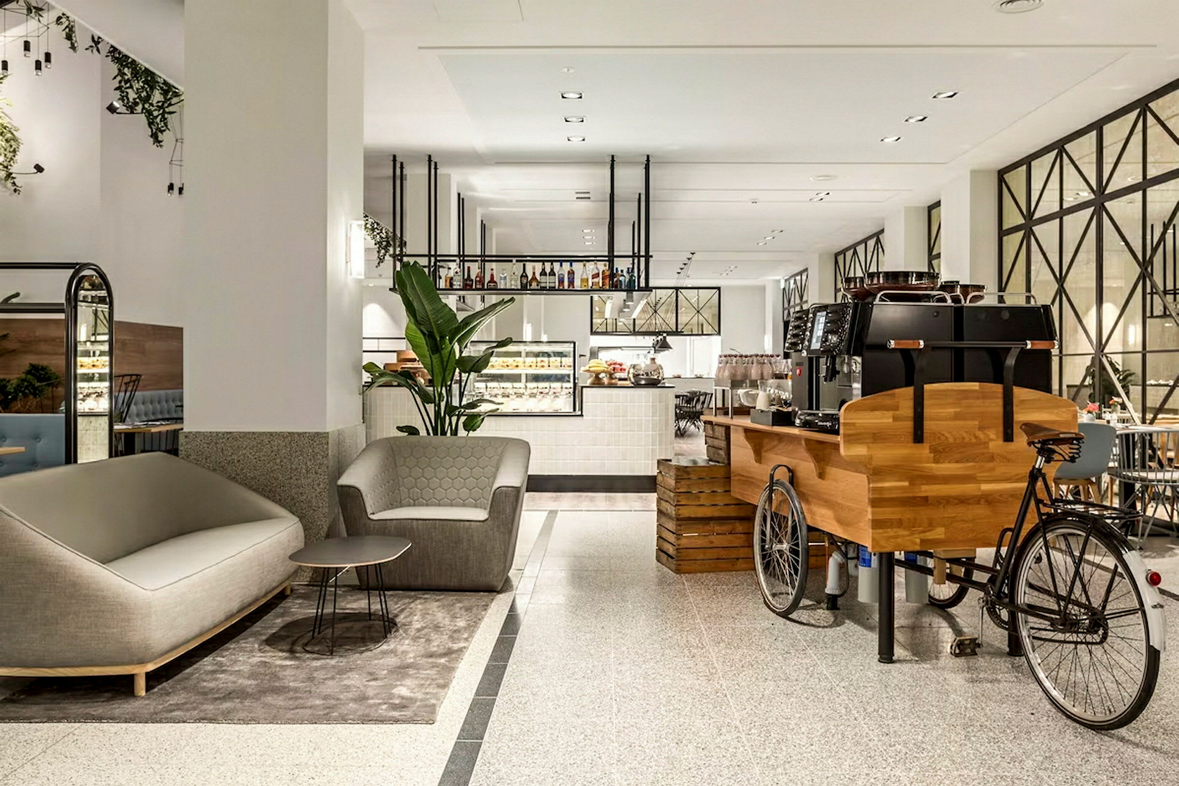 Moderne kafé med sitteplasser og unik kaffemaskin på sykkel. (AI-generert tekst)