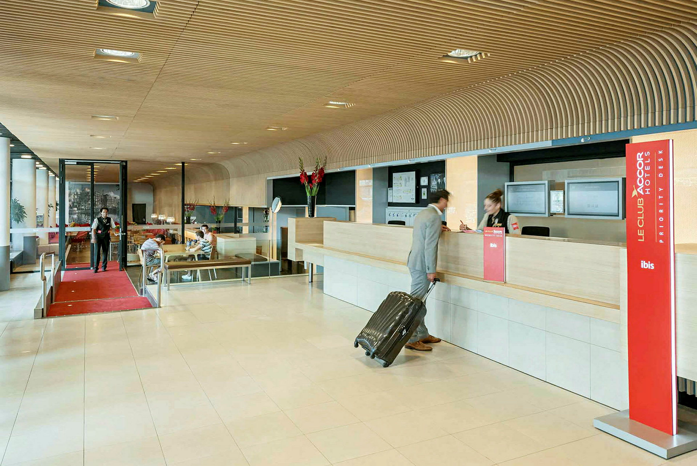 Hotellobby med resepsjon, en person med koffert sjekker inn. (AI-generert tekst)
