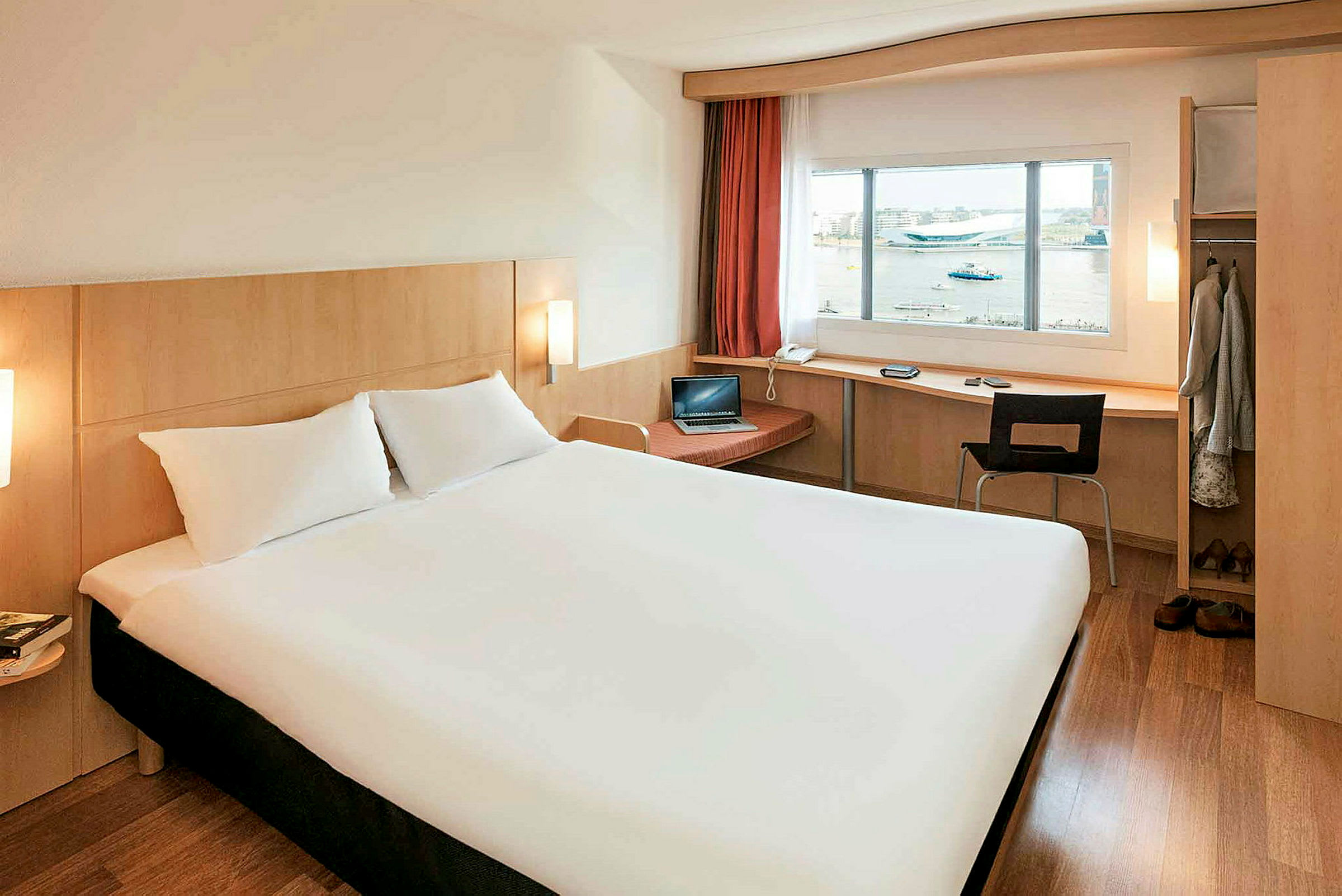 Et hotellrom med en stor seng, skrivebord ved vinduet og garderobe. (AI-generert tekst)