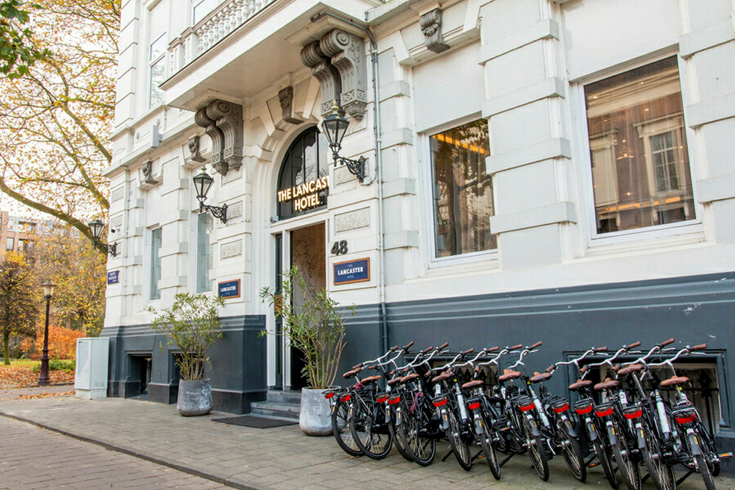 Inngang til et hotell med sykler parkert langs bygningens fasade. (AI-generert tekst)
