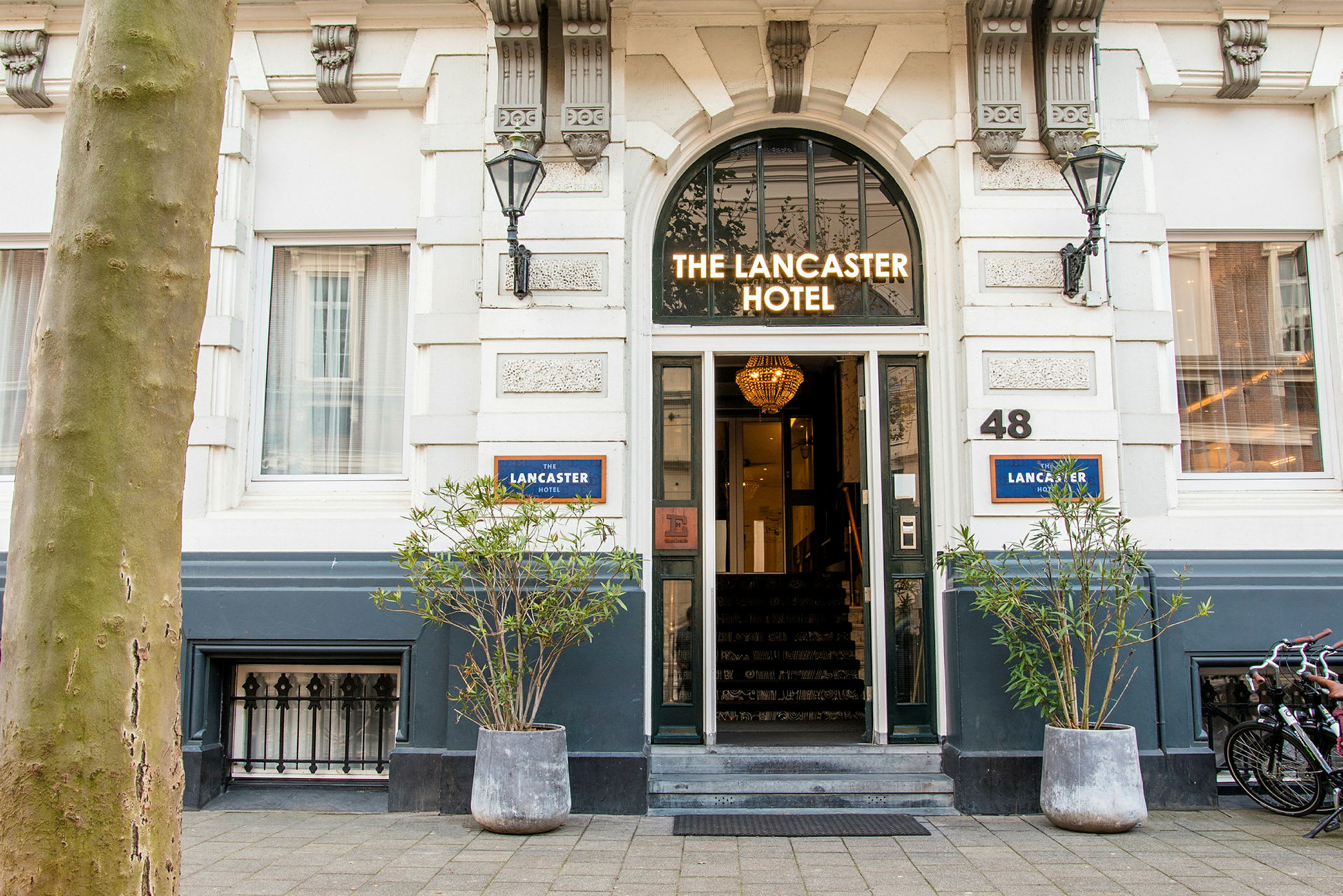 Inngang til et hotell med skiltet 'The Lancaster Hotel' over døren. (AI-generert tekst)
