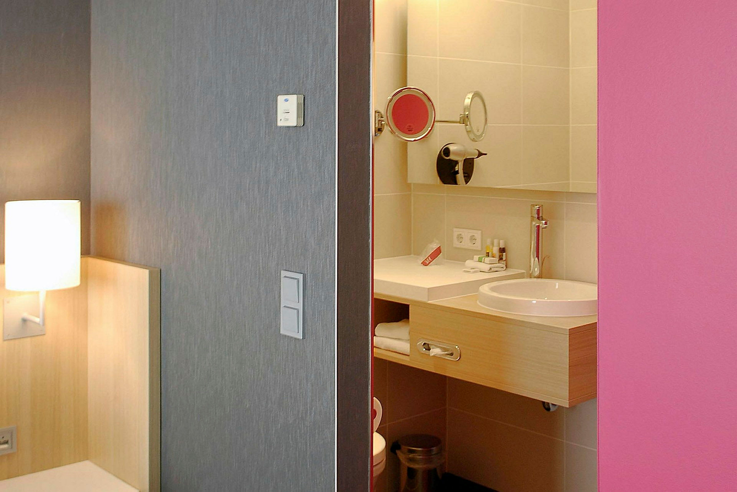 Hotellrom med utsikt over badet, lampen og sengens hjørne synlige. (AI-generert tekst)