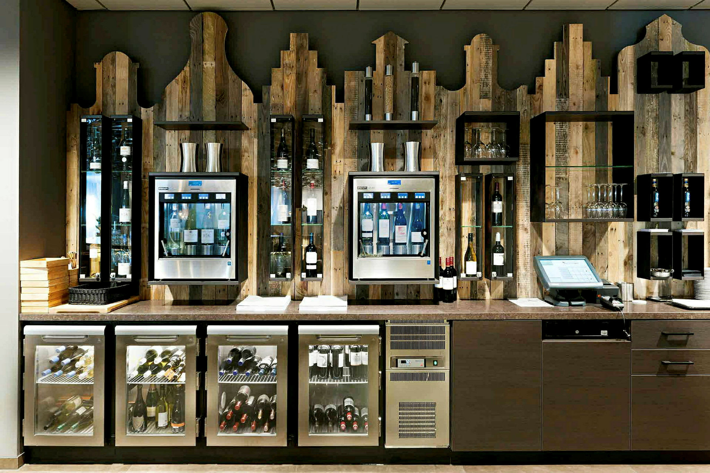 En vinbar med flasker og glass er plassert mot en trevegg. (AI-generert tekst)
