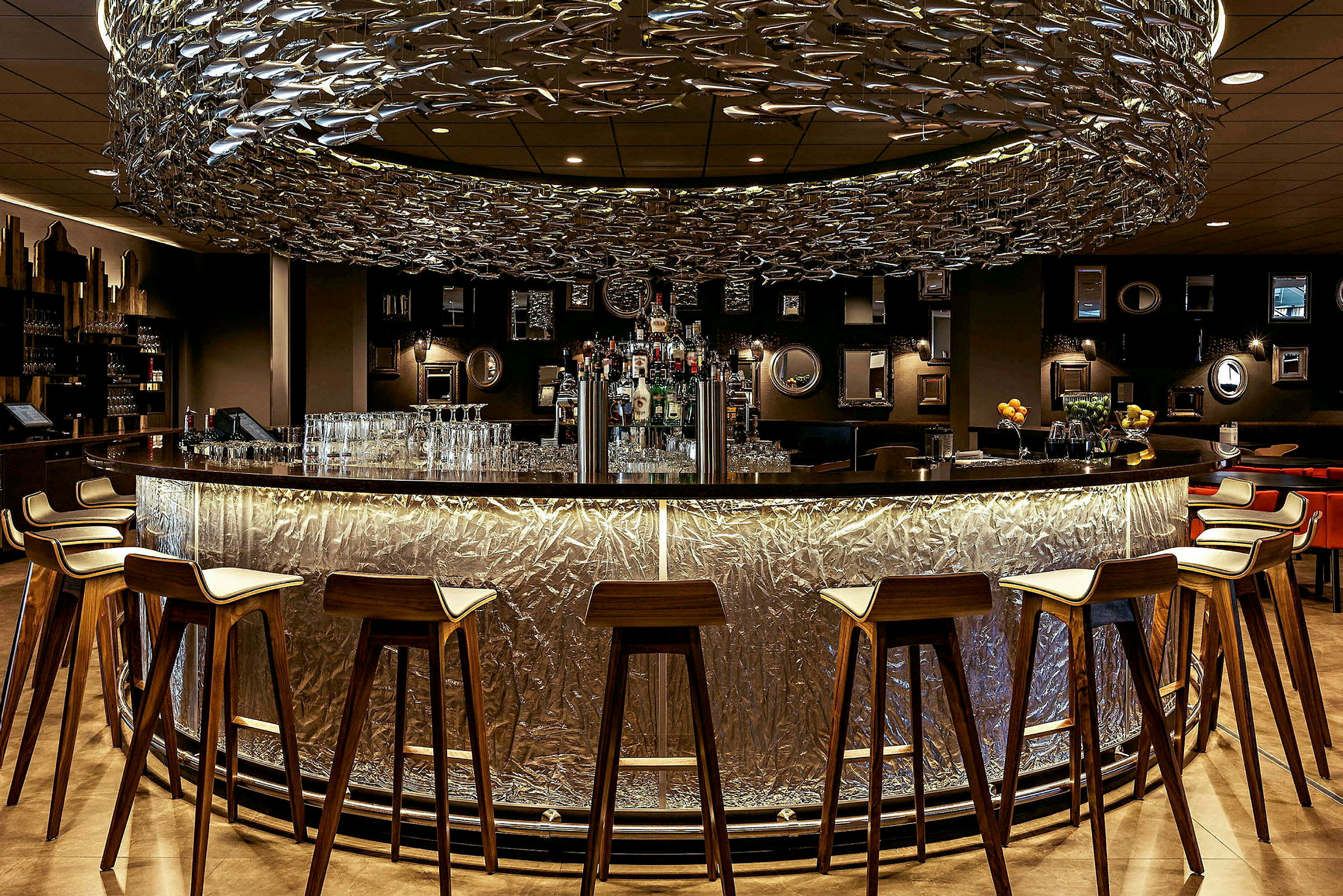 En rund bardisk med høye stoler og en unik takdekorasjon. (AI-generert tekst)