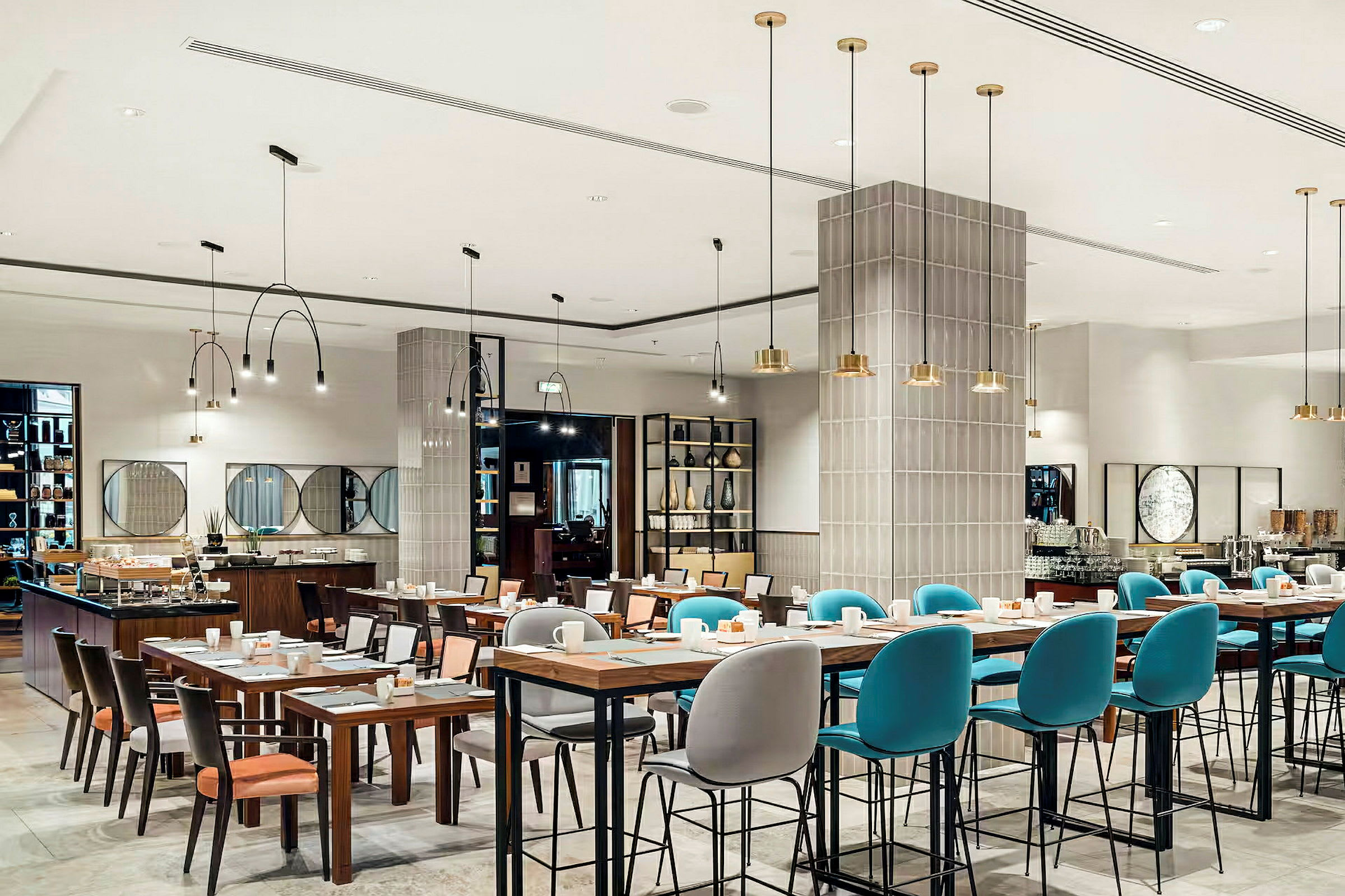 En moderne restaurant med dekkede bord og stoler, samt taklamper som henger ned fra taket. (AI-generert tekst)