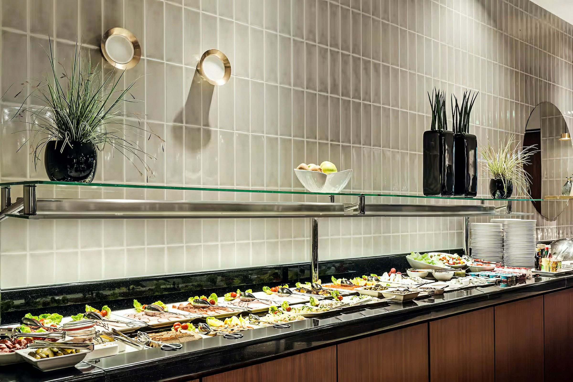 Bilde av en bufférestaurant med et utvalg tallerkener og ulike matretter og tilbehør lagt ut på en svart overflate under en glasshylle. (AI-generert tekst)