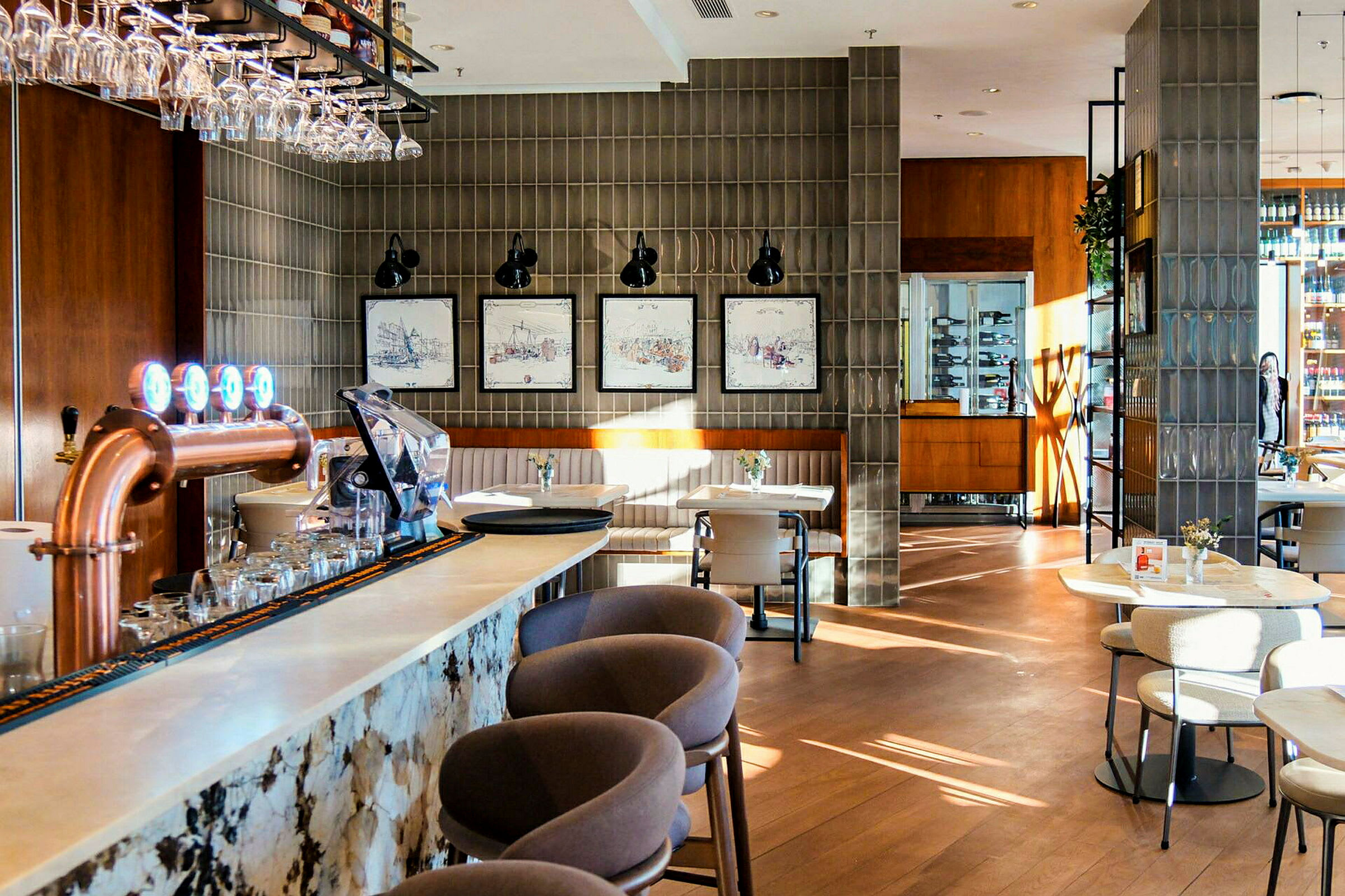 En stilfull restaurantinnredning med en bardisk i forgrunnen, stoler og bord spredt rundt i lokalet, samt dekorasjoner og planter. (AI-generert tekst)
