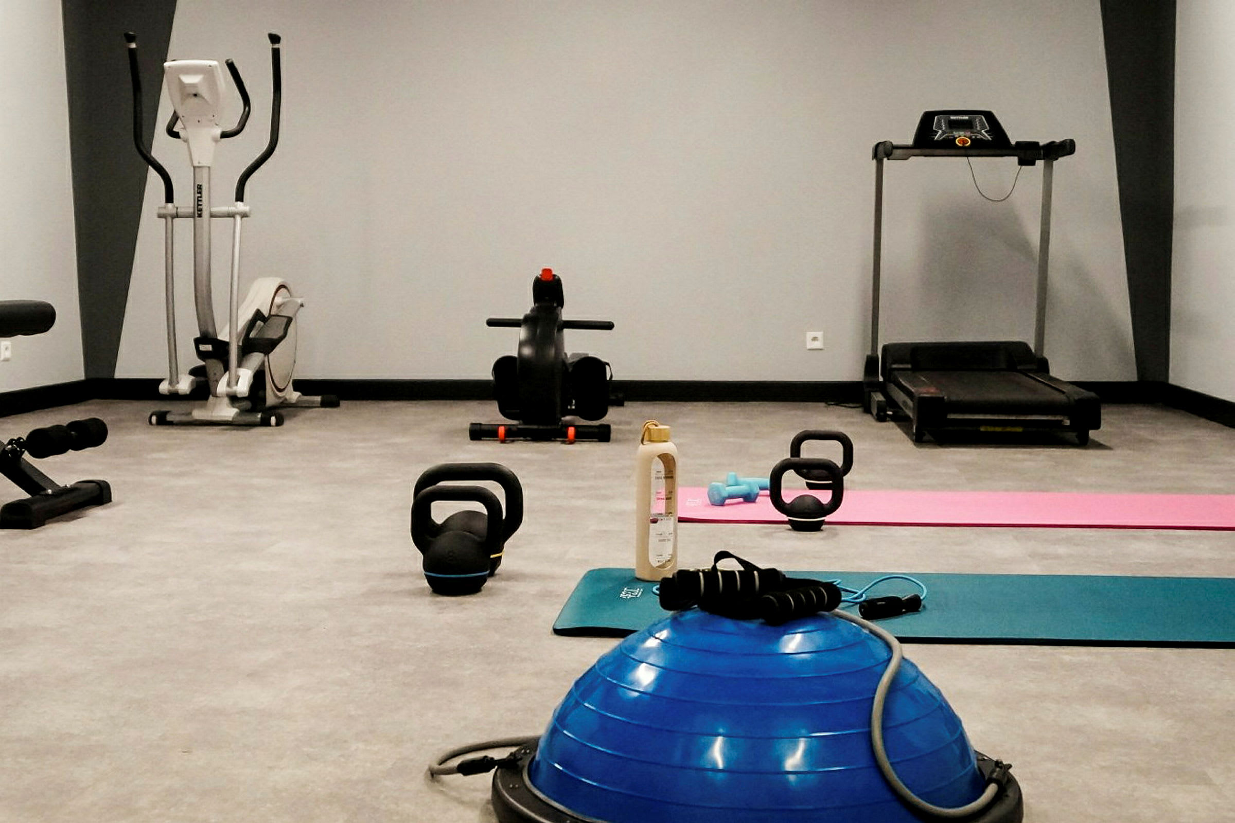 Et treningsstudio med treningsmaskiner, kettlebells og treningsmatter. (AI-generert tekst)