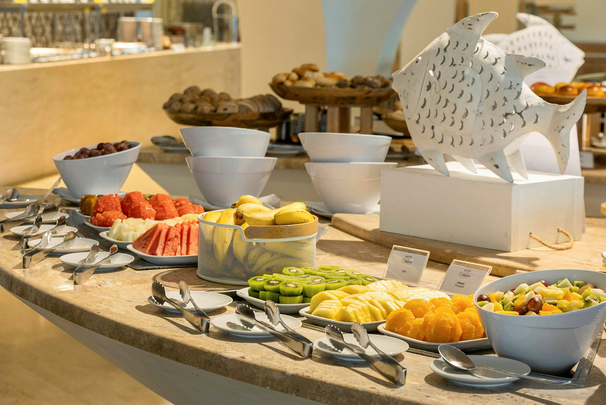 En buffet med ulike typer skivet frukt og brød lagt opp på et bord. (AI-generert tekst)