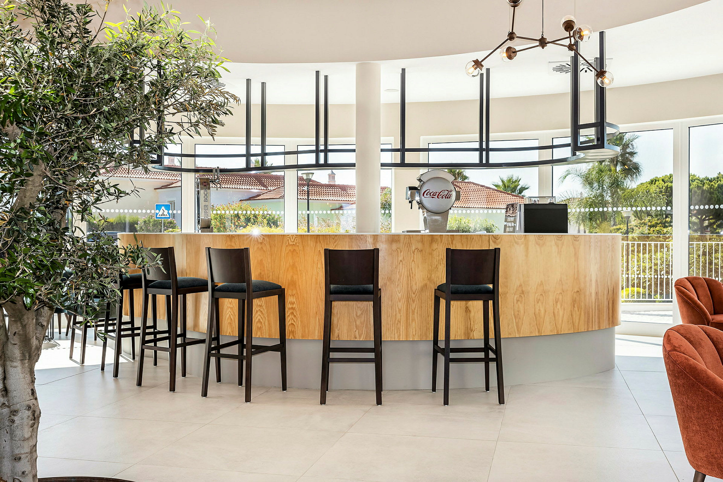 En moderne bar med høye stoler og store vinduer. (AI-generert tekst)