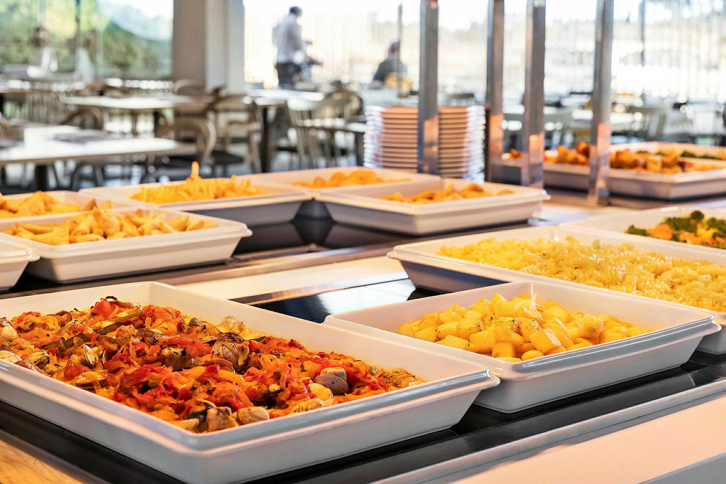 Bilde av en buffet med forskjellige retter, inkludert poteter, pasta og grønnsaker, servert i hvite serveringsboller. (AI-generert tekst)