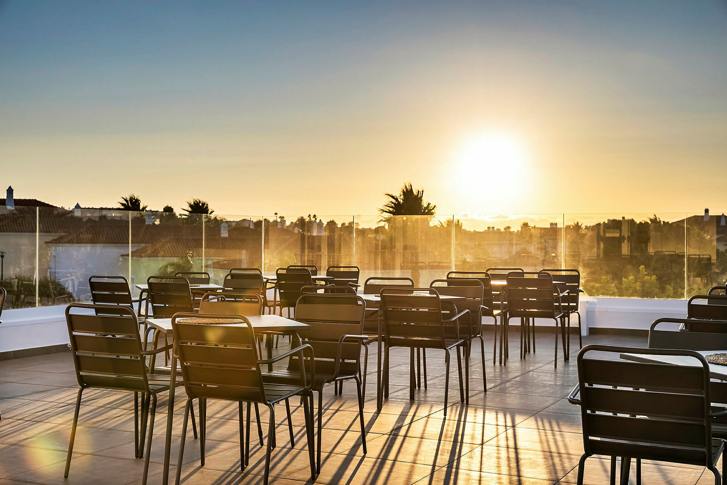 En terrasse med bord og stoler ved solnedgang. (AI-generert tekst)