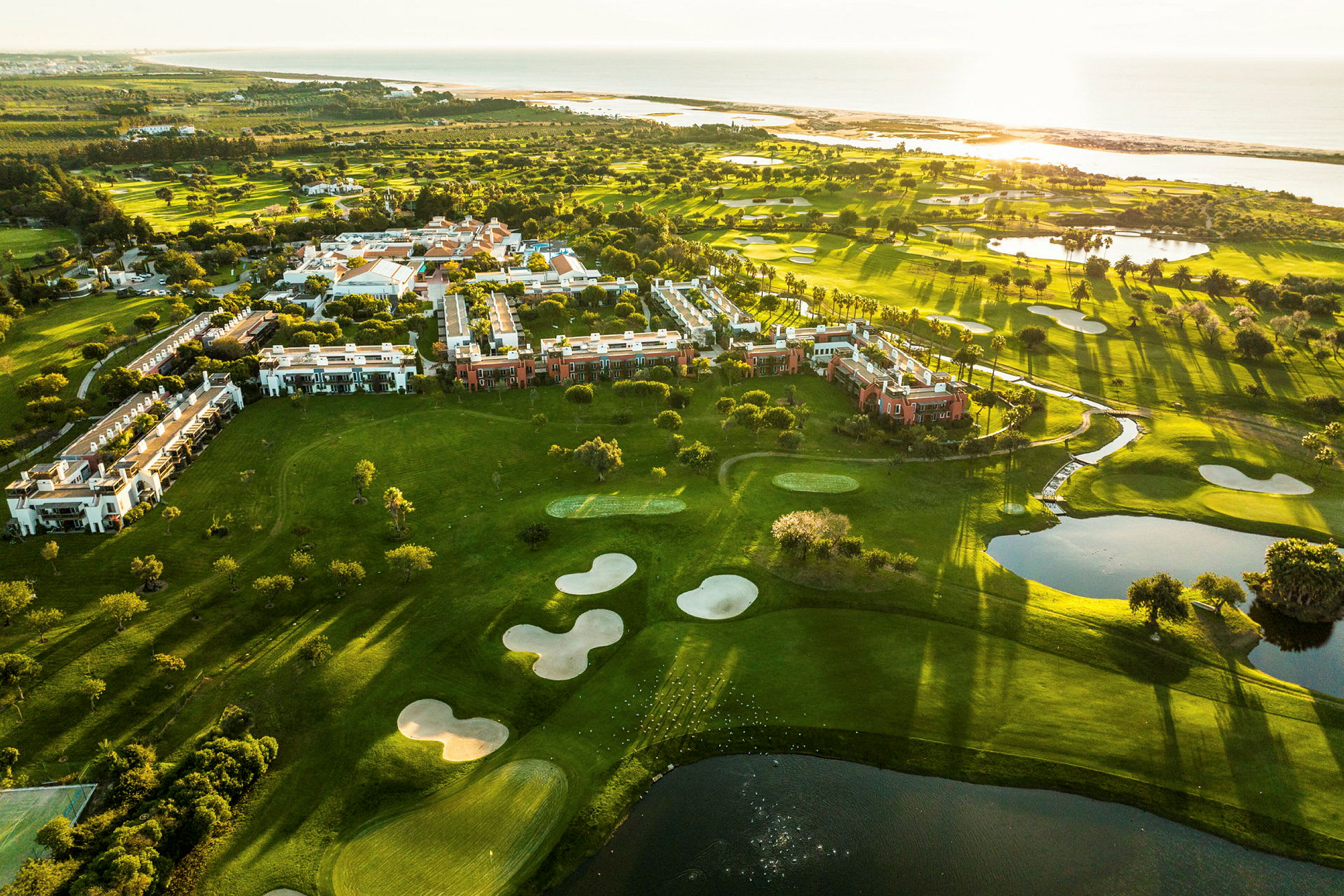 Luftfoto av grønne områder med bygninger og golfbaner ved havet. (AI-generert tekst)