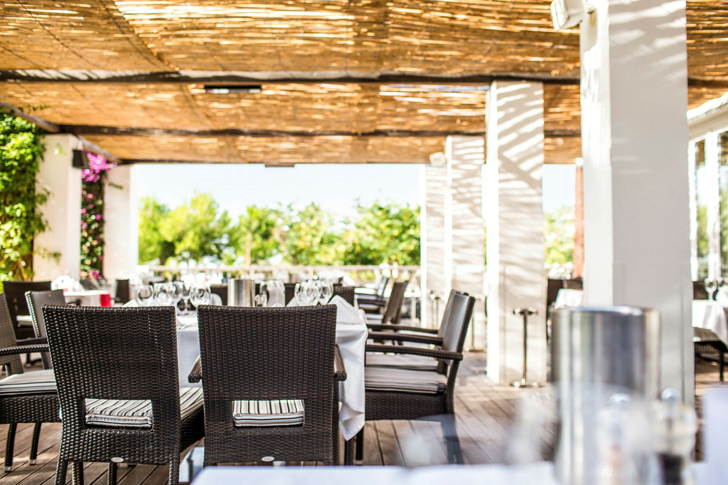 En utendørsrestaurant med dekkede bord under en pergola. (AI-generert tekst)
