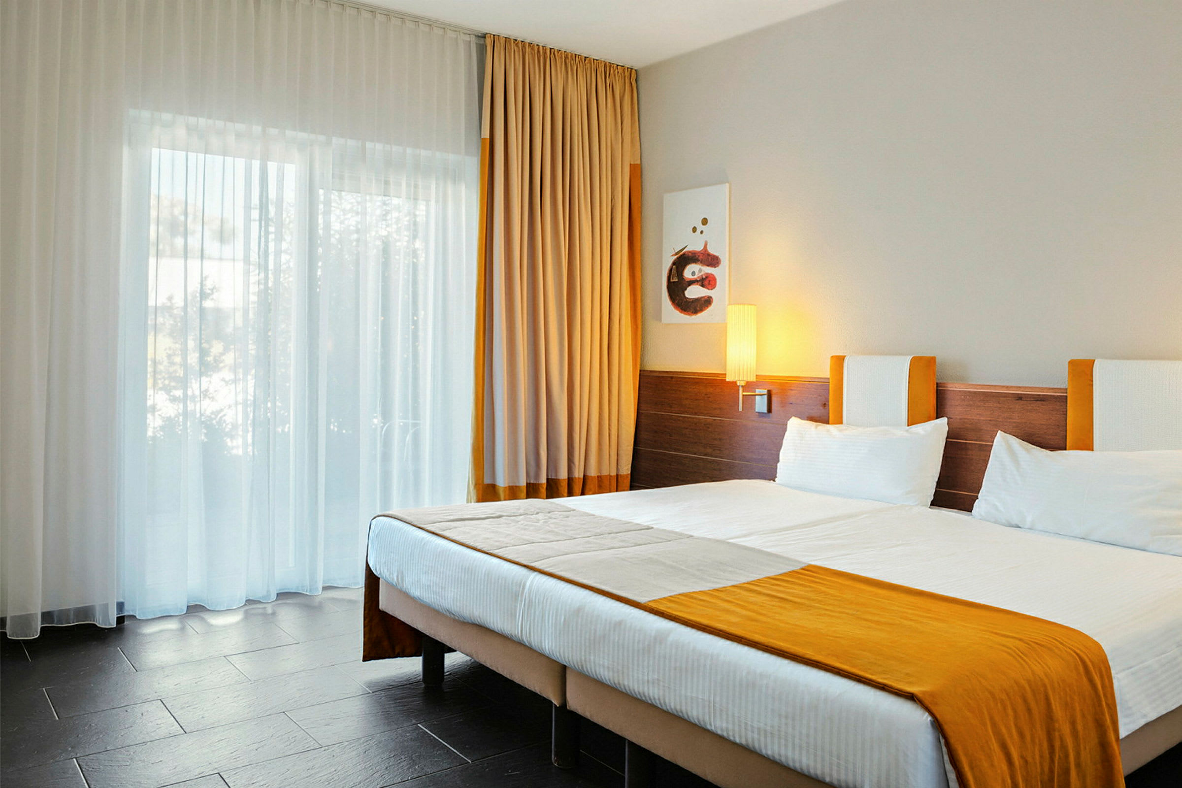 Et hotellrom med en dobbeltseng og oransje detaljer. (AI-generert tekst)