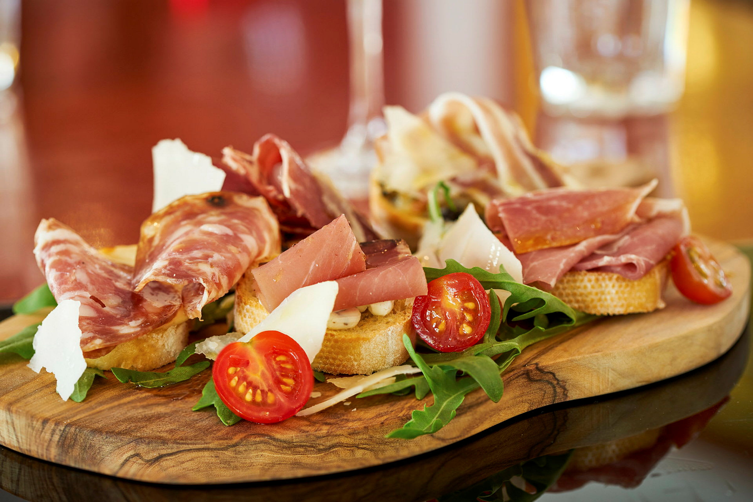 En trefat med antipasti inkludert skiver av spekemat, cherrytomater, ruccola og ost. (AI-generert tekst)