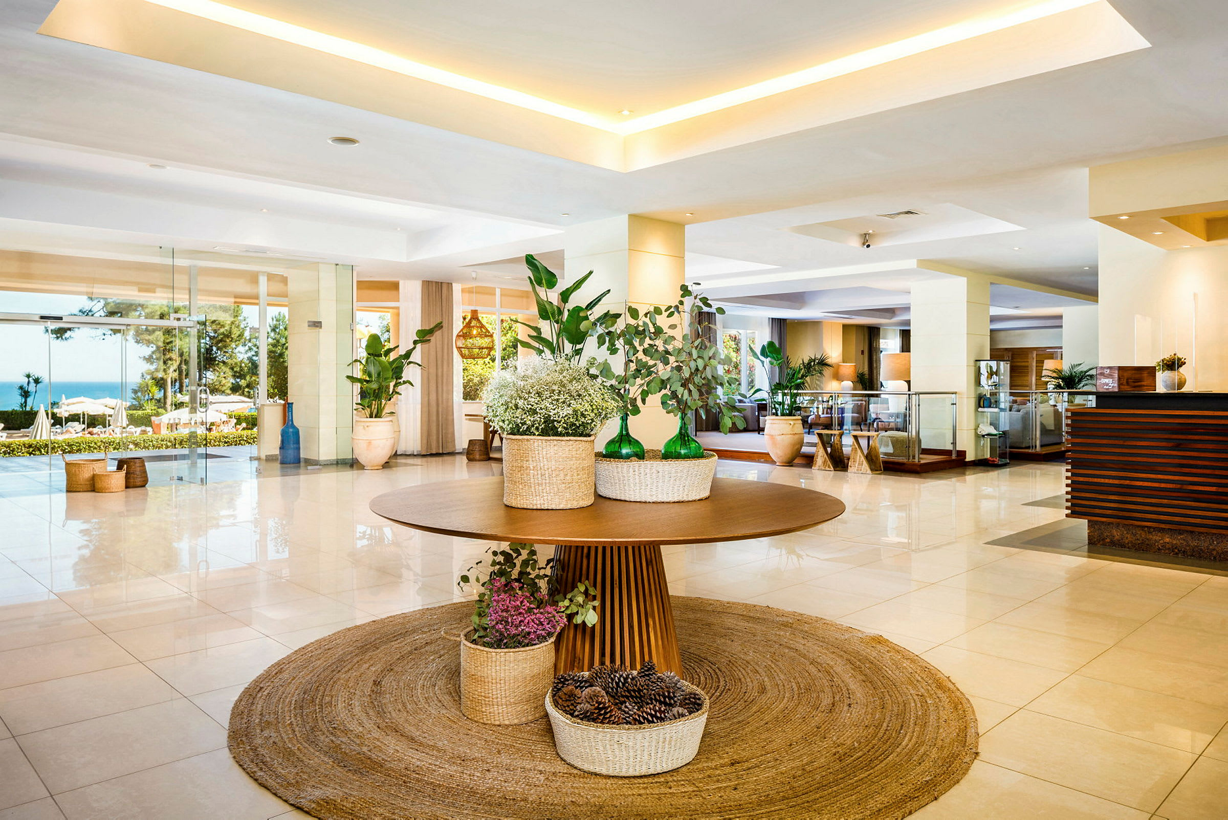 Hotellobby med et dekorert bord med planter og kurver på et rundt teppe. (AI-generert tekst)