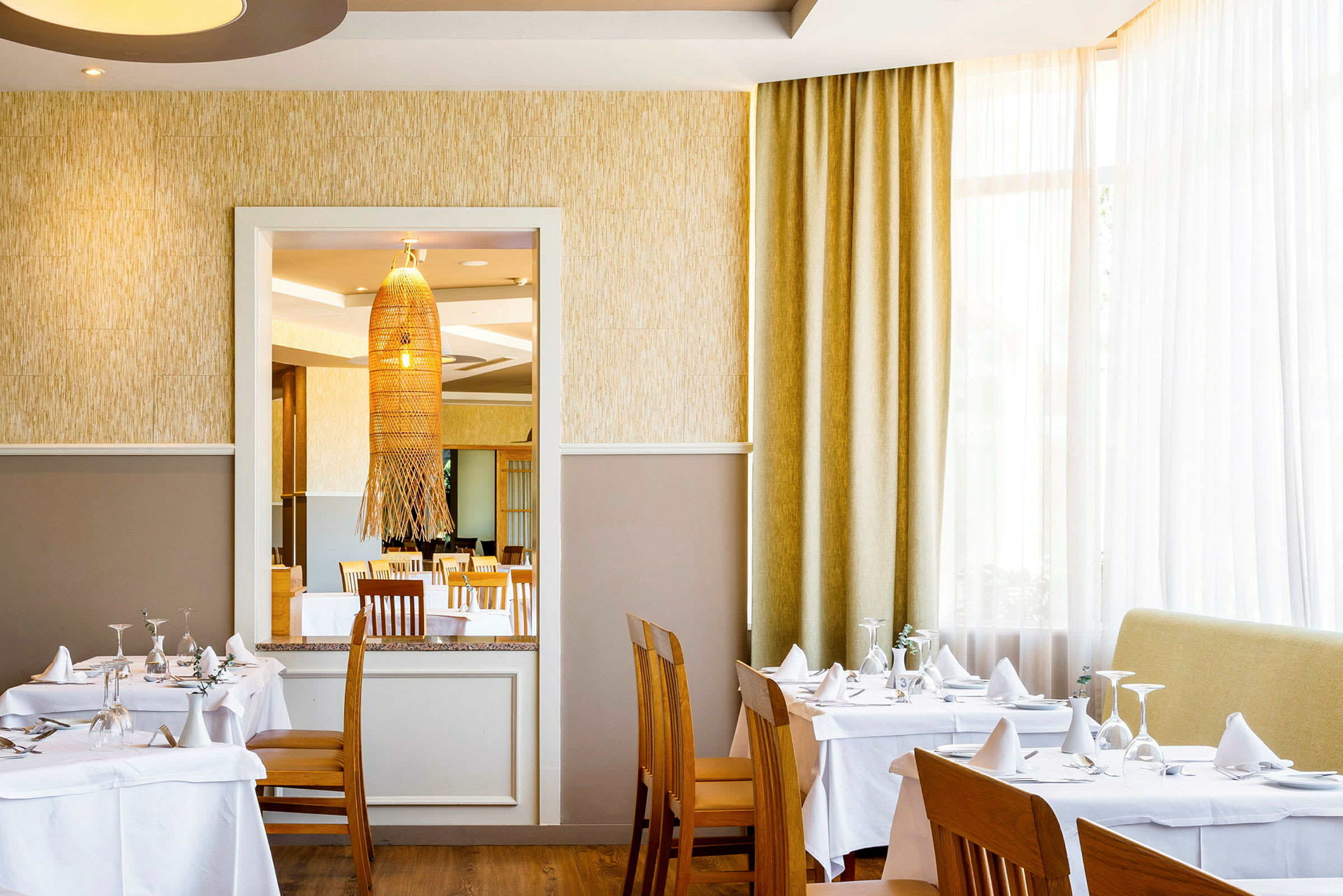 Interiør av en restaurant med dekkede bord og stoler. (AI-generert tekst)