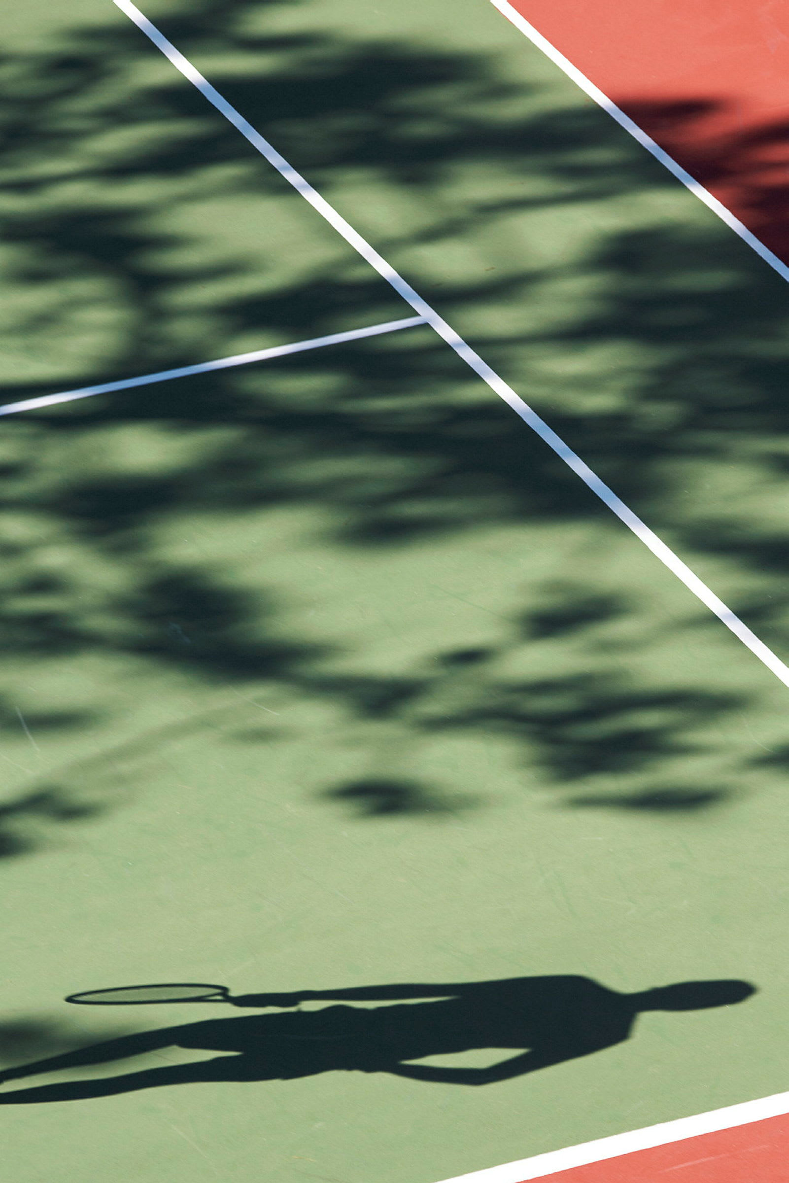 Skygge av en person med tennisracket på en tennisbane. (AI-generert tekst)