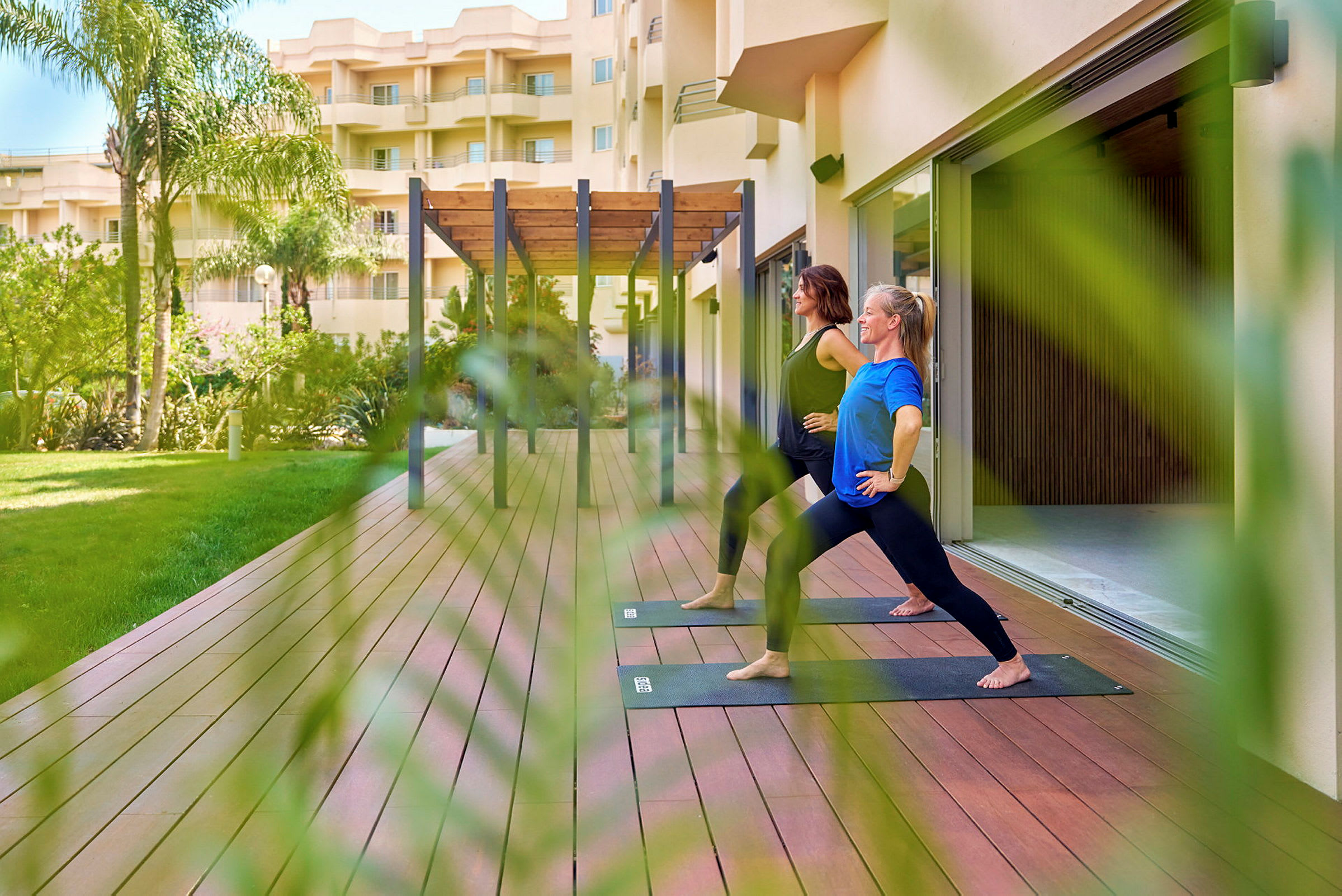 Personer utøver yoga på en treplattform utendørs nær en bygning. (AI-generert tekst)