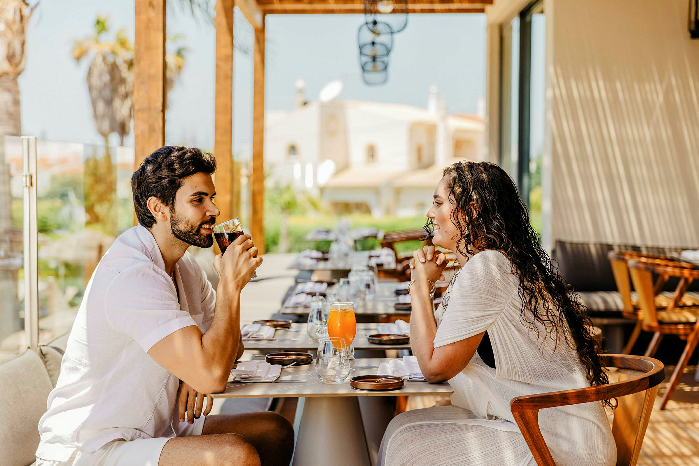 To personer sitter ved et dekket restaurantbord og drikker drikke. (AI-generert tekst)